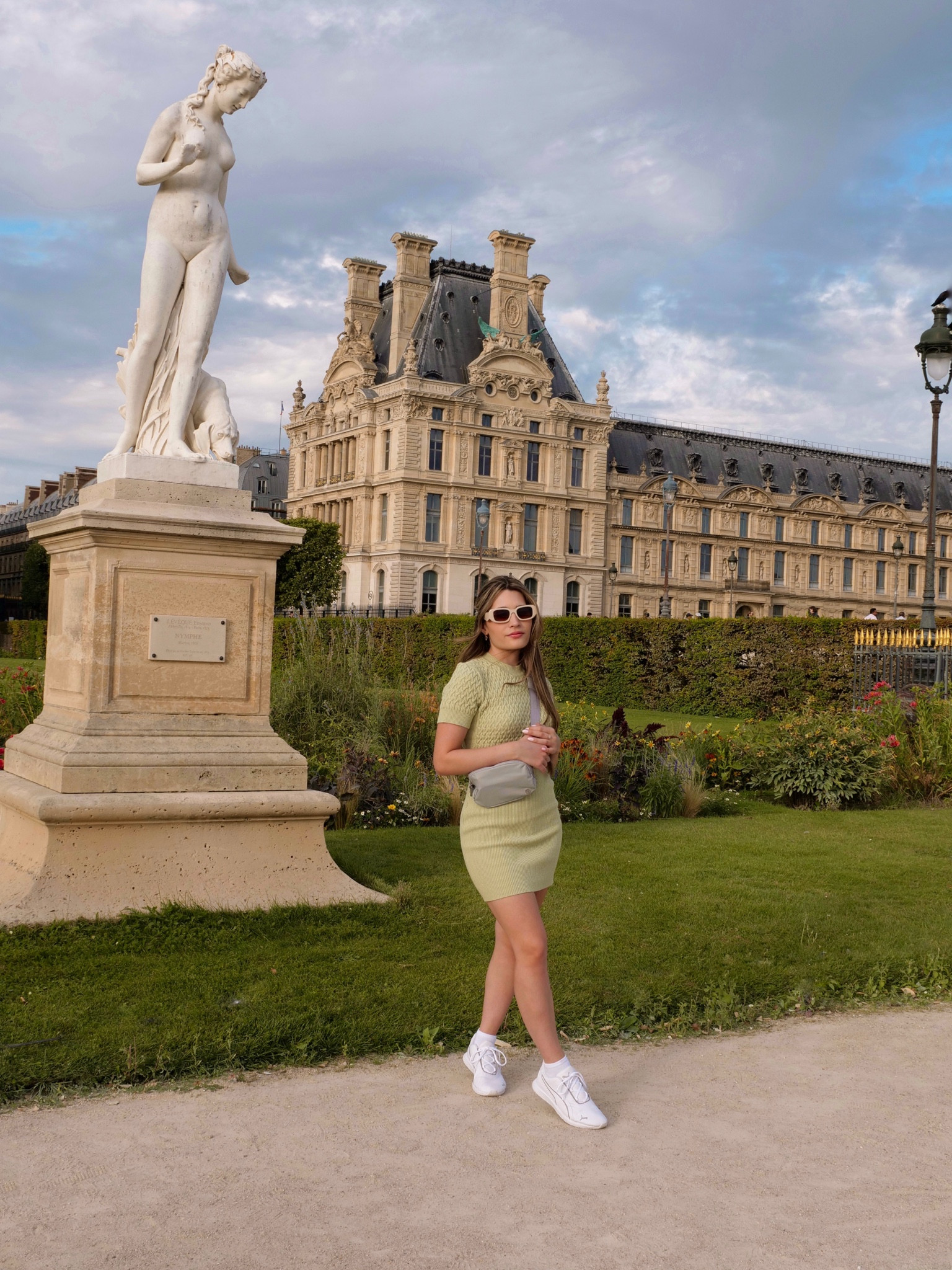 Strolling at the jardin du tuileries in Paris wearing storets green knit bodycon dress, lululemon everywhere belt bag in silver drop, urban outfitters cream sunnies, and puma Ella sneakers
