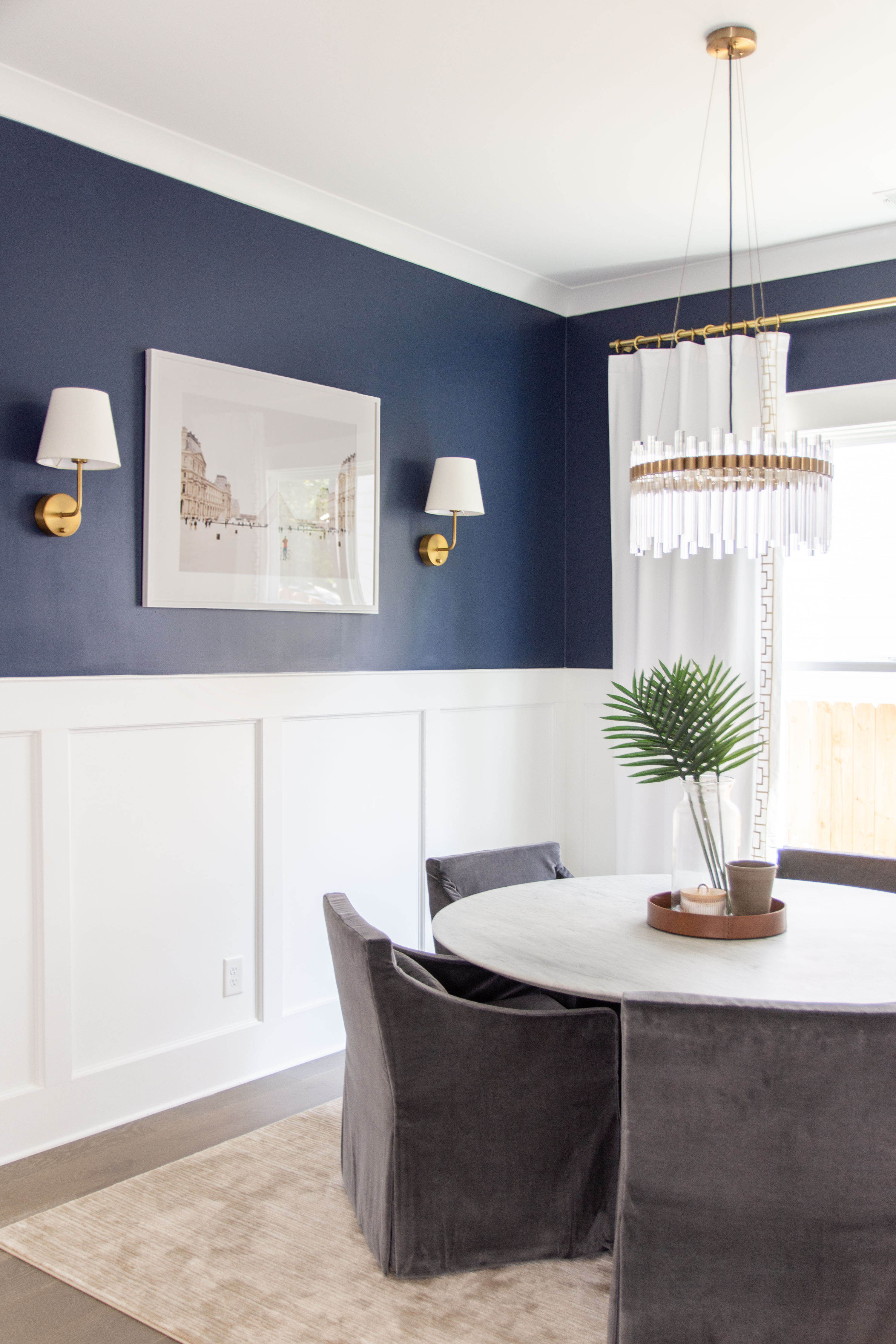 Navy blue dining room design with marble round dining table, tulip table, gray slipcover dining chairs, modern crystal chandelier, and brass sconces

#LTKHome #LTKStyleTip