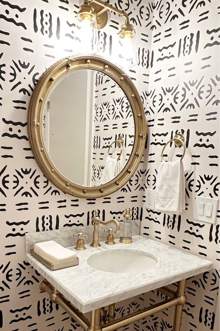 Powder room with black and white peel and stick wallpaper, gold faucet, gold round mirror, 2 light vanity light, marble top brass console vanity #home #bath #powderroom #design #interiors #remodel 

#LTKsalealert #LTKstyletip #LTKhome