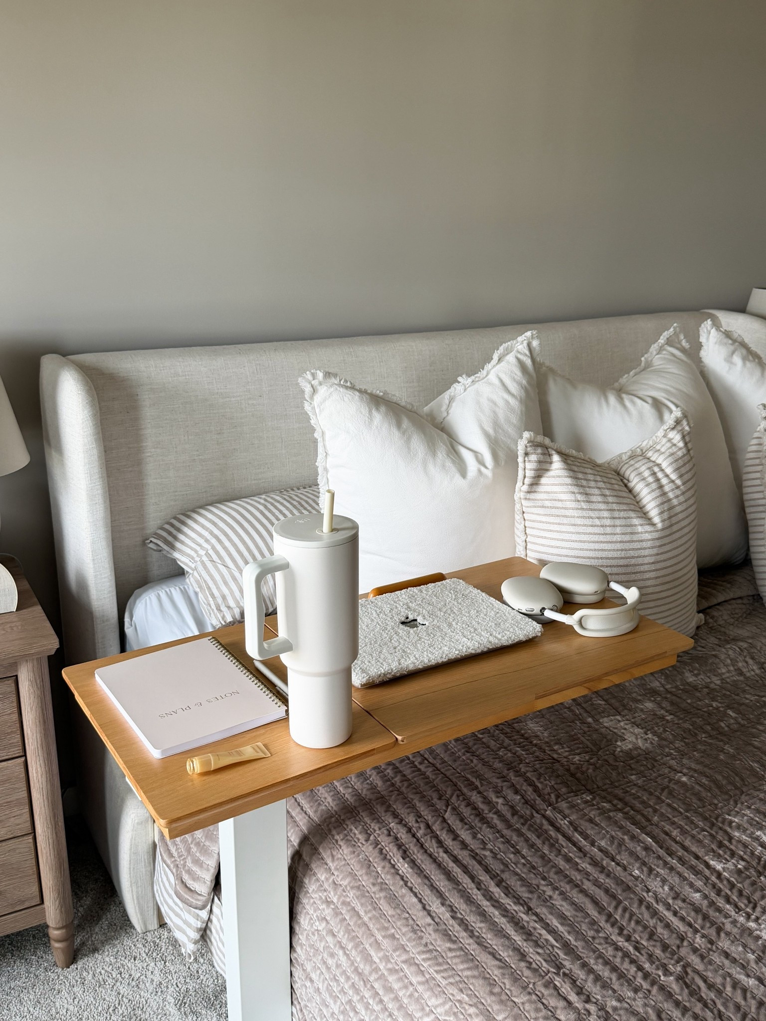 My cozy work from bed setup lately 🤍 Shop this bedside laptop table, neutral bedding, upholstered bed frame, striped pillows, oversized tumbler, headphones, notebook, and cozy bedroom essentials. Perfect for creating a functional and aesthetic bedroom workspace, reading nook, or lazy day setup with warm neutral decor. #bedroomdecor #cozyhome #workfromhome #neutraldecor #ltkhome

#LTKHome