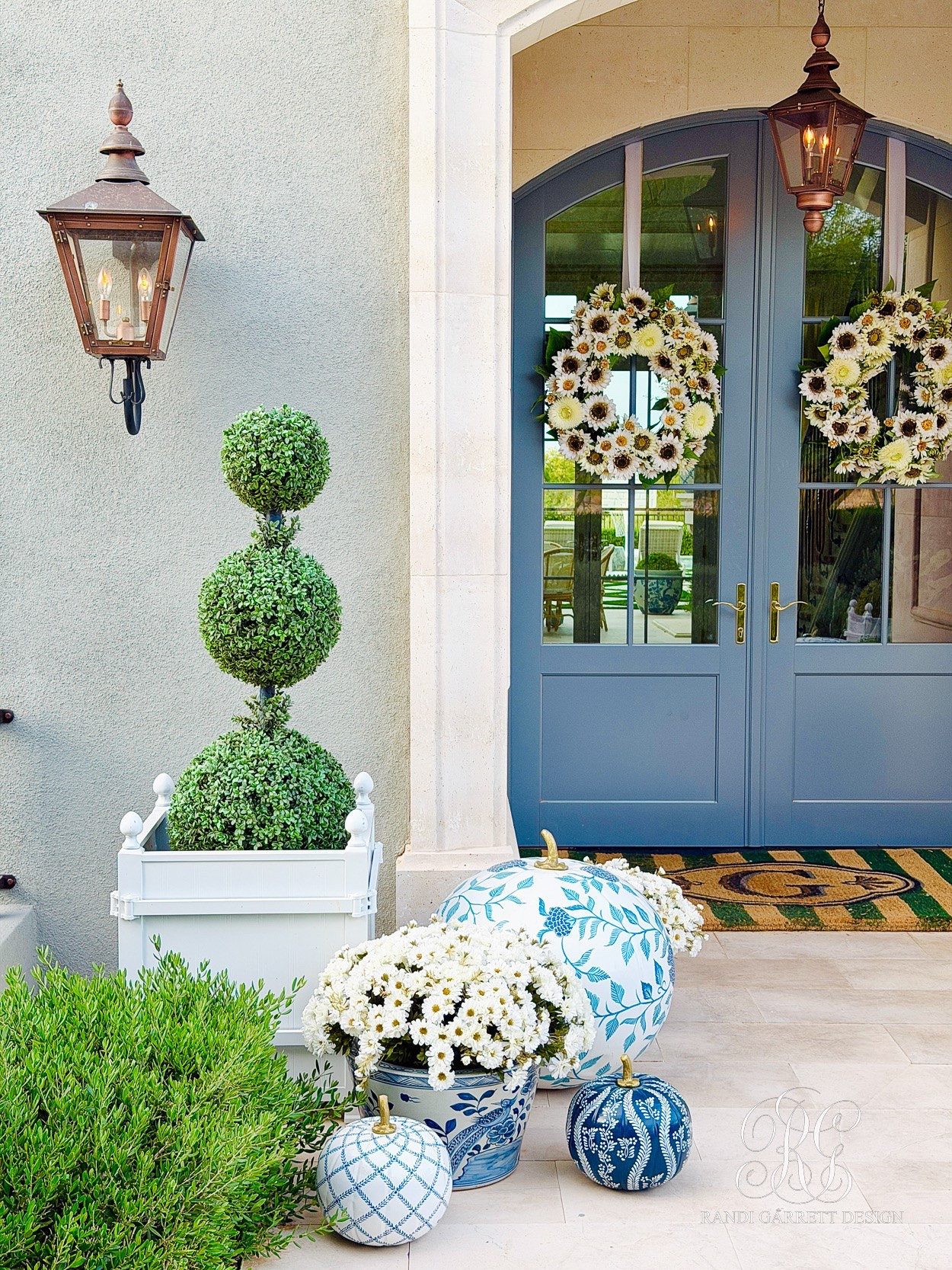 Blue and white fall porch! You’ll love these sunflower wreaths, blue and white pumpkins, faux zinnias and boxwood topiaries. The monogrammed doormat comes in single and double door sizes. The French planters also come in several colors.