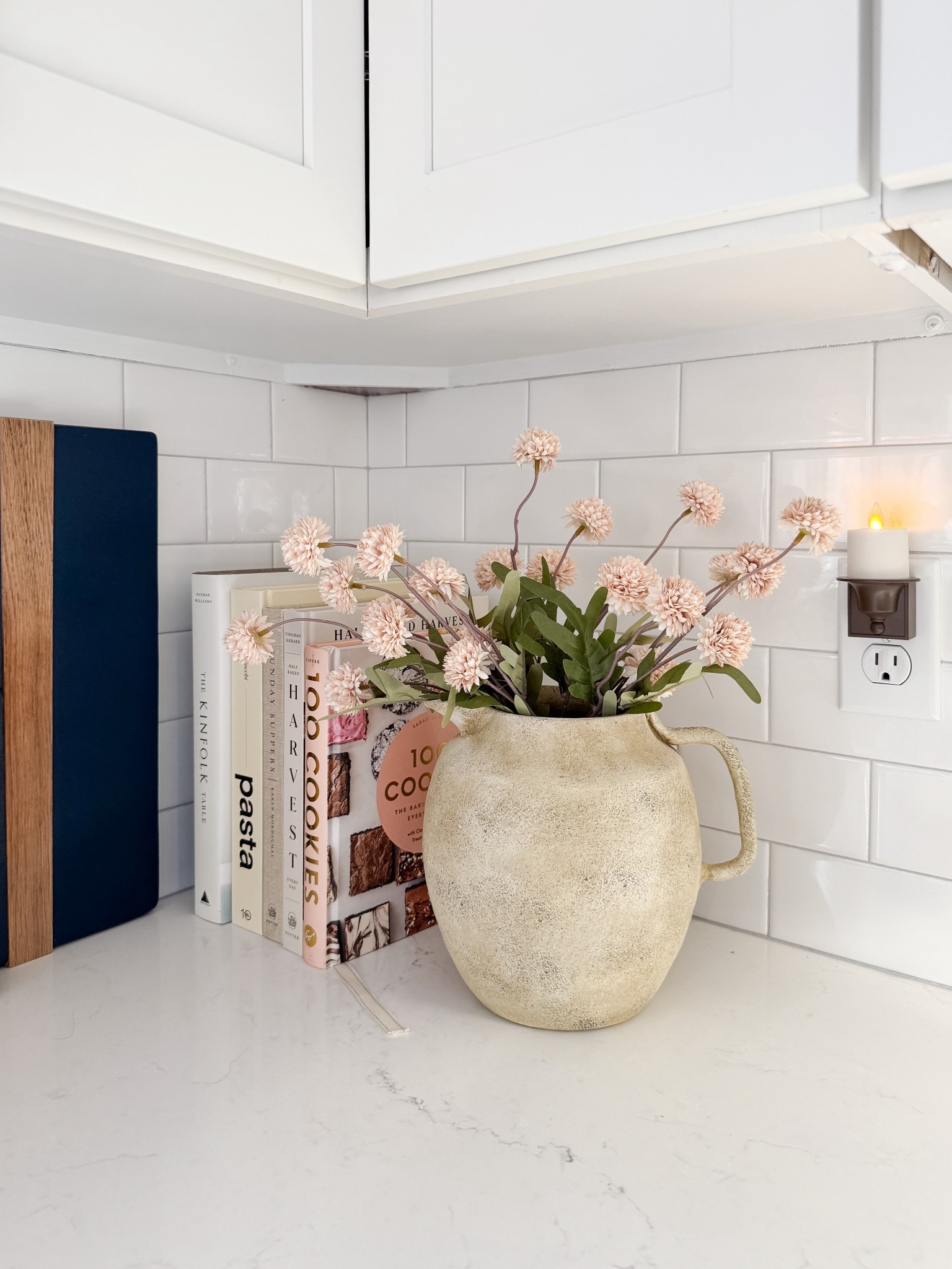 Kitchen counter styling with textured ceramic pitcher vase, soft blush florals, stacked cookbooks, and white subway tile backsplash. Warm neutral kitchen decor for a simple seasonal refresh. 
kitchen counter decor, ceramic pitcher vase, spring kitchen decor, cookbooks styling, subway tile kitchen, neutral kitchen, blush florals, kitchen styling ideas, coastal kitchen decor, simple home refresh, cottage kitchen, everyday decor, sherri calnan home

#LTKHome