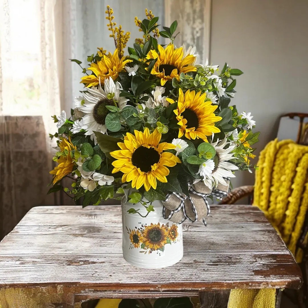 Bring bold farmhouse charm into your home with this tall sunflower and daisy arrangement, designed to brighten any space. Set in a classic white milk can with a charming sunflower detail, this piece is full and eye-catching from every angle with vibrant yellow blooms and lush greenery. The buffalo plaid bow adds a cozy, rustic touch (and can be removed for a simpler look), making it perfect for seasonal decorating, entryways, or as a standout table centerpiece. #LTKhome #farmhousedecor #sunflowerdecor #floralarrangement #rusticstyle #homedecorinspo #countryliving #etsyhome

#LTKWedding #LTKHome #LTKSeasonal
