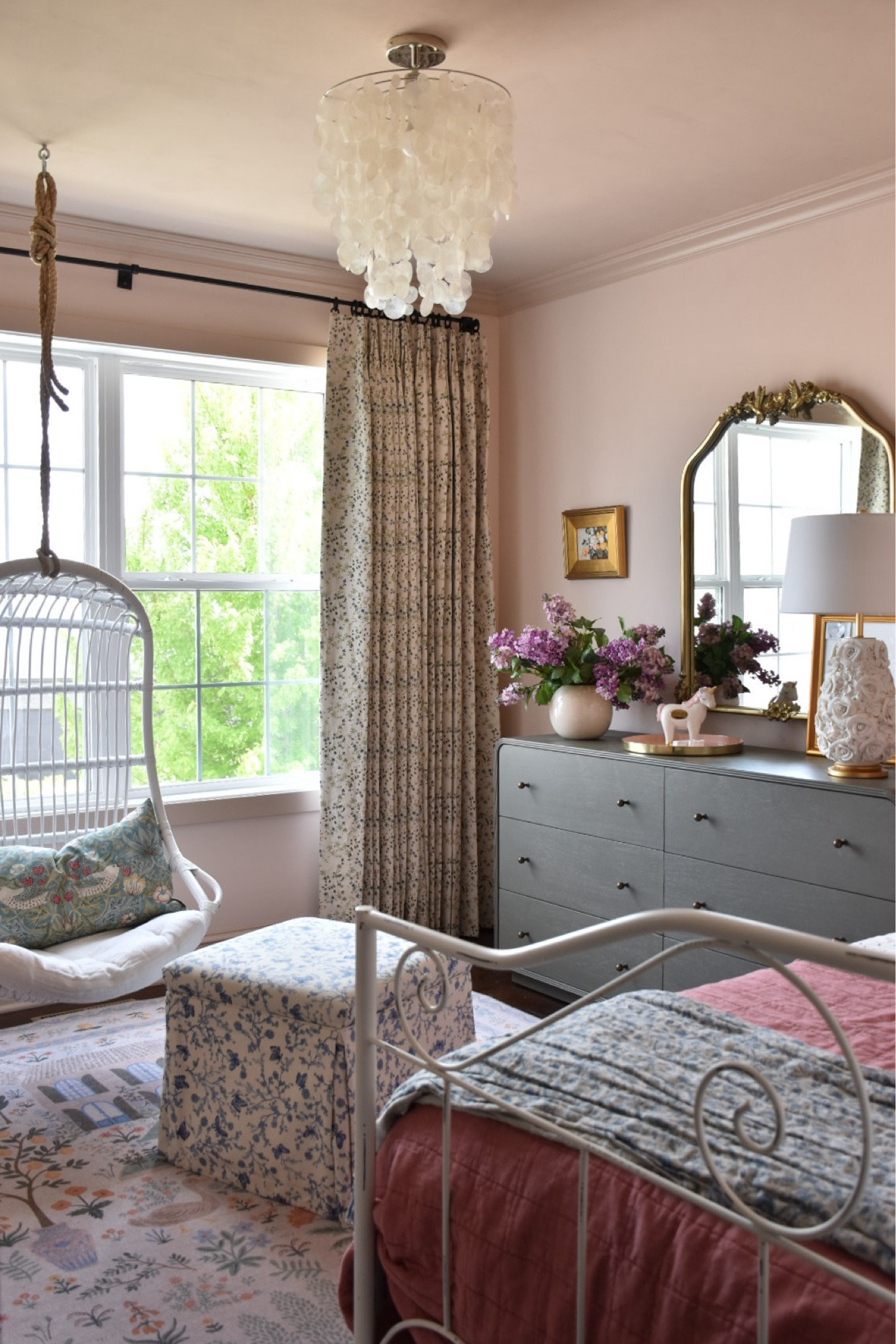 Pink little girls room that can easily transition into a teen bedroom. This whimsical bedroom design features floral patterns, storage ottoman, a gold mirror, hanging rattan chair and affordable bedding, floral art and a playful rug.

#LTKSaleAlert #LTKKids #LTKHome