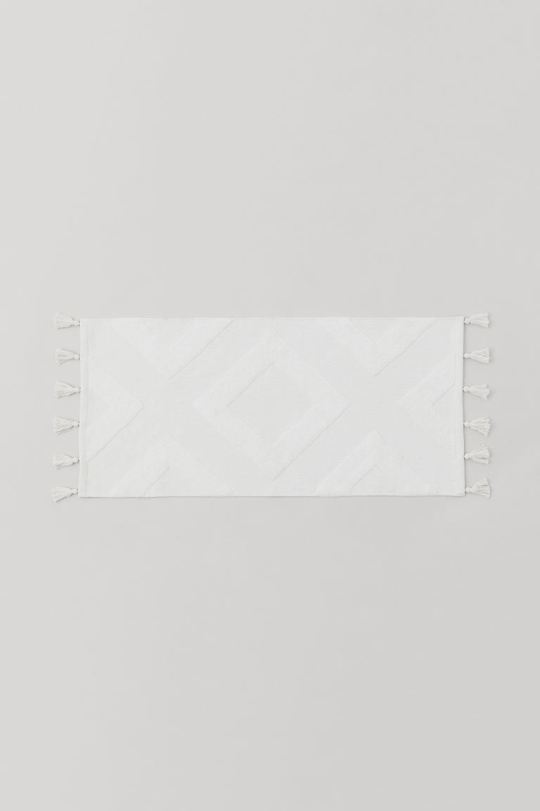 Bath mat in thick, woven cotton fabric with a tufted graphic pattern. Tassels at short sides and ... | H&M (US + CA)