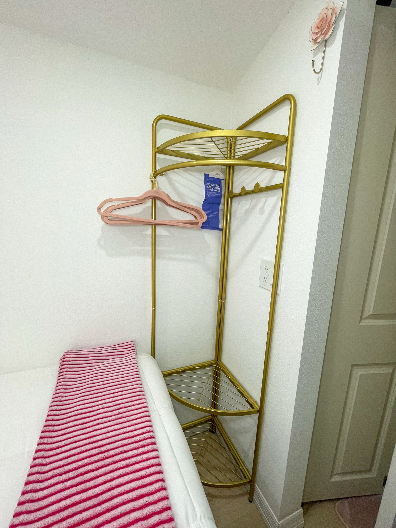 Pretty gold closet rack and blush accents — maximizing tiny-space storage in style.
