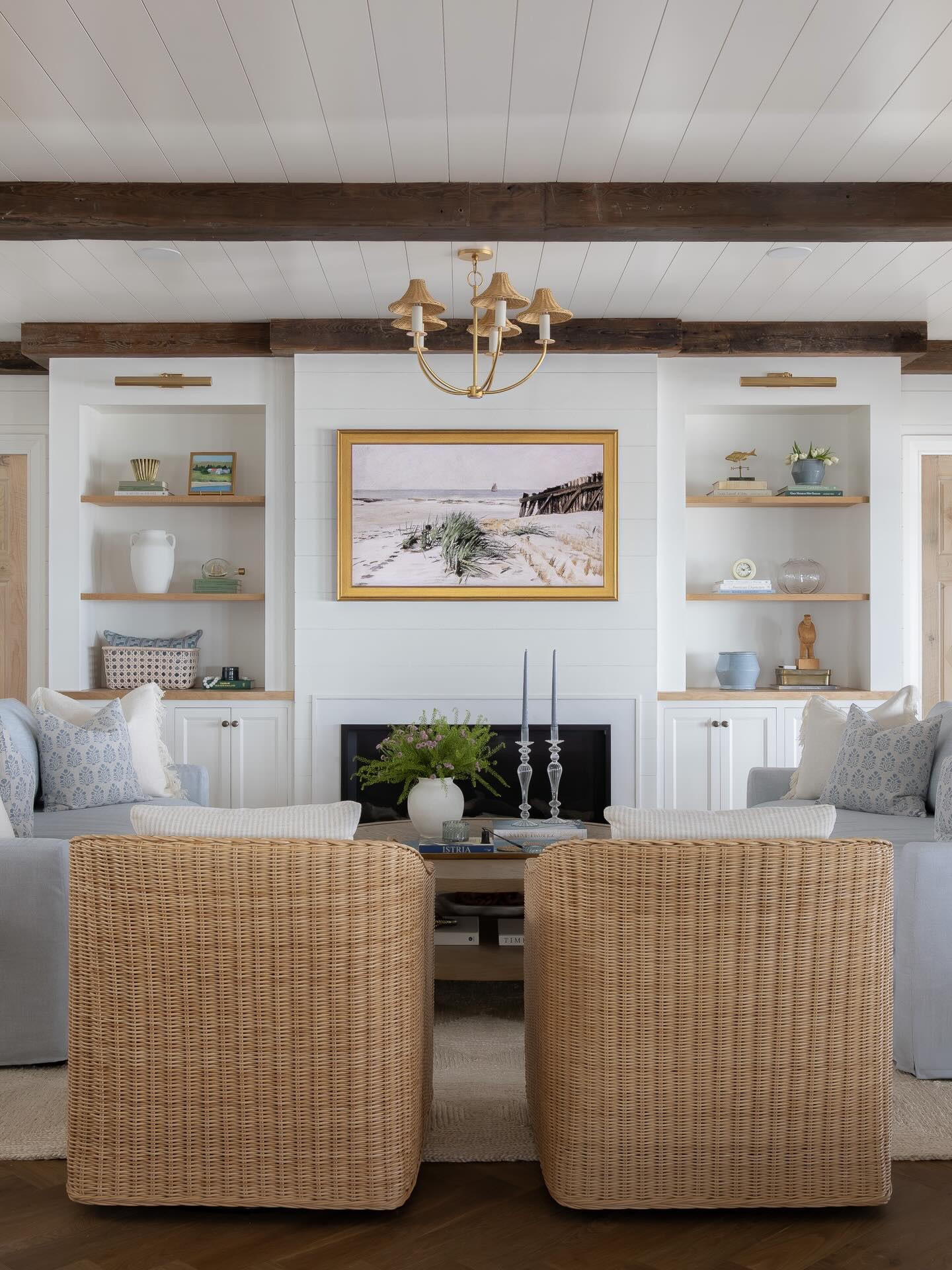 The living room at our Humarock Project is one of our favorite spaces we’ve ever done. The simplicity of white shiplap with rustic pine beams is a combination we’ll never get tired of and this room allows them to be the star of the show. 

We designed these custom built ins and diamond pocket doors to create symmetry, storage and a place to showcase beautiful things. When our client told us they wanted sky blue sofas we said ok how about two!? We love how the mirrored sofas add to the summetry and create the perfect spot for hanging with friends by the fire or watching tv. 

The cherry on top is the styling which makes the space feel like home. The vintage fishermen, ship in a bottle and mix of local art are some of our favorite things we’ve ever found. Using a mix of old and new makes a new house feel like a home with soul which was always our goal for this new build by the ocean. 

Design @pennyandpearldesign 
Photos @marinaporl
