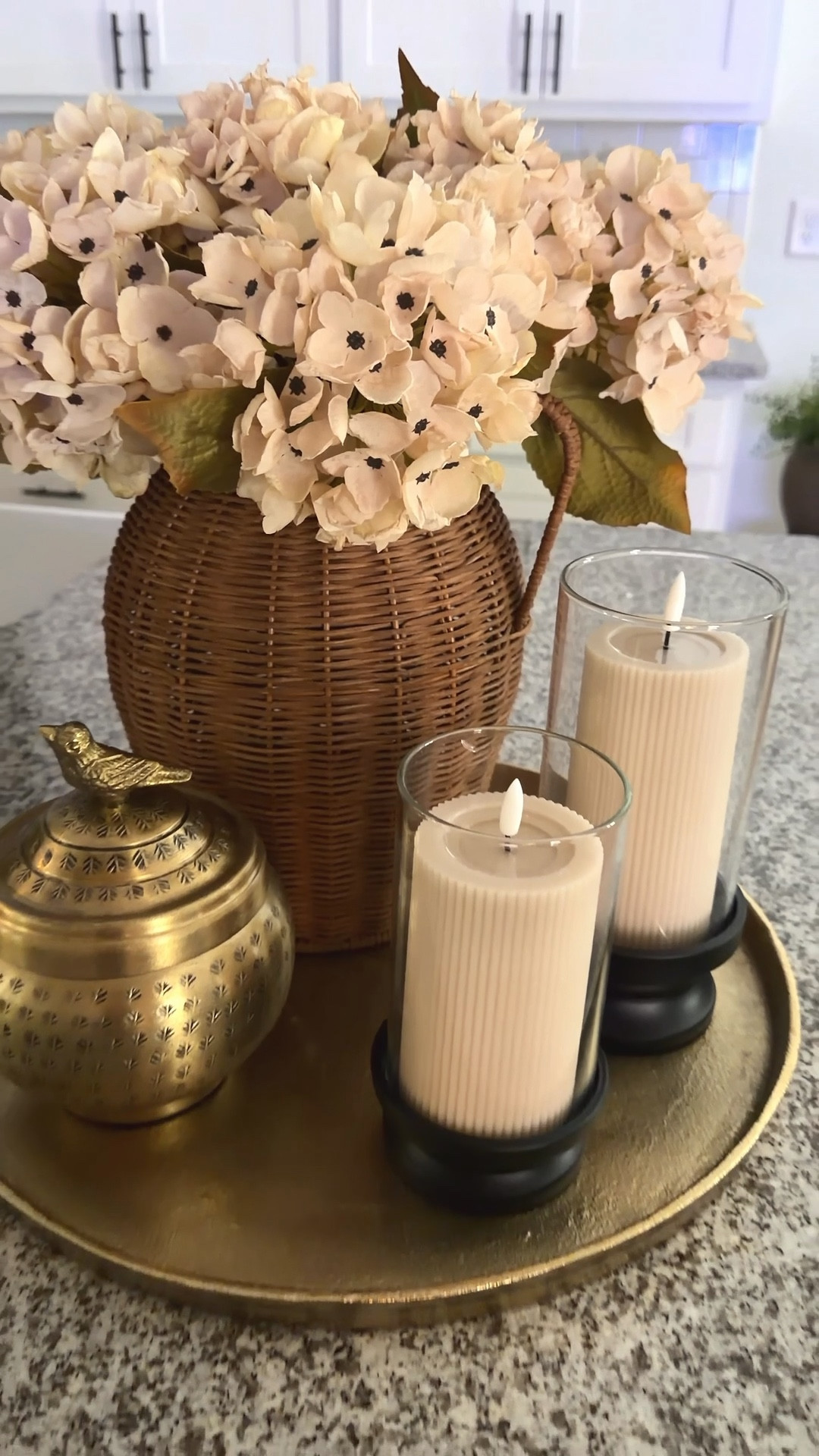 If you love neutrals…this one’s calling your name. 🤎

These creamy hydrangeas are the perfect starting point for a soft, layered centerpiece. I paired them with a rattan vase for texture, added some budget-friendly hurricane candles for that cozy glow, and finished it off with the prettiest little canister topped with a sweet bird.