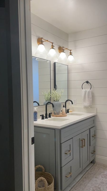 Our kids bathroom is bright with a gray 48” vanity that we converted into a double vanity. 

Bathroom gray vanity.  Black bathroom mirrors.  Brass lighting.  Wall mounted lights.  Black Kingston brass faucets.  

#LTKHome #LTKFamily #LTKVideo