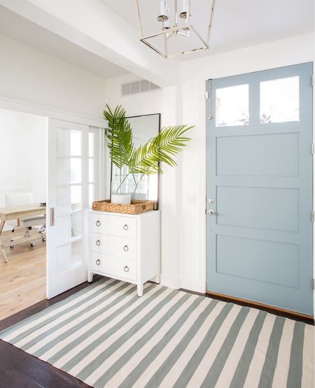 Our Omaha entryway decorated for summer with a white glossy raffia cabinet, blue and cream striped rug, lantern pendant light, “It Is Well” canvas art, tall thin black framed mirror, faux palm leaves and a paint dipped vase.

#ltkhome #ltkseasonal #ltkstyletip #ltkfindsunder50 #ltkunder100  coastal decorating, foyer ideas, blue and white

#LTKhome #LTKsalealert #LTKSeasonal