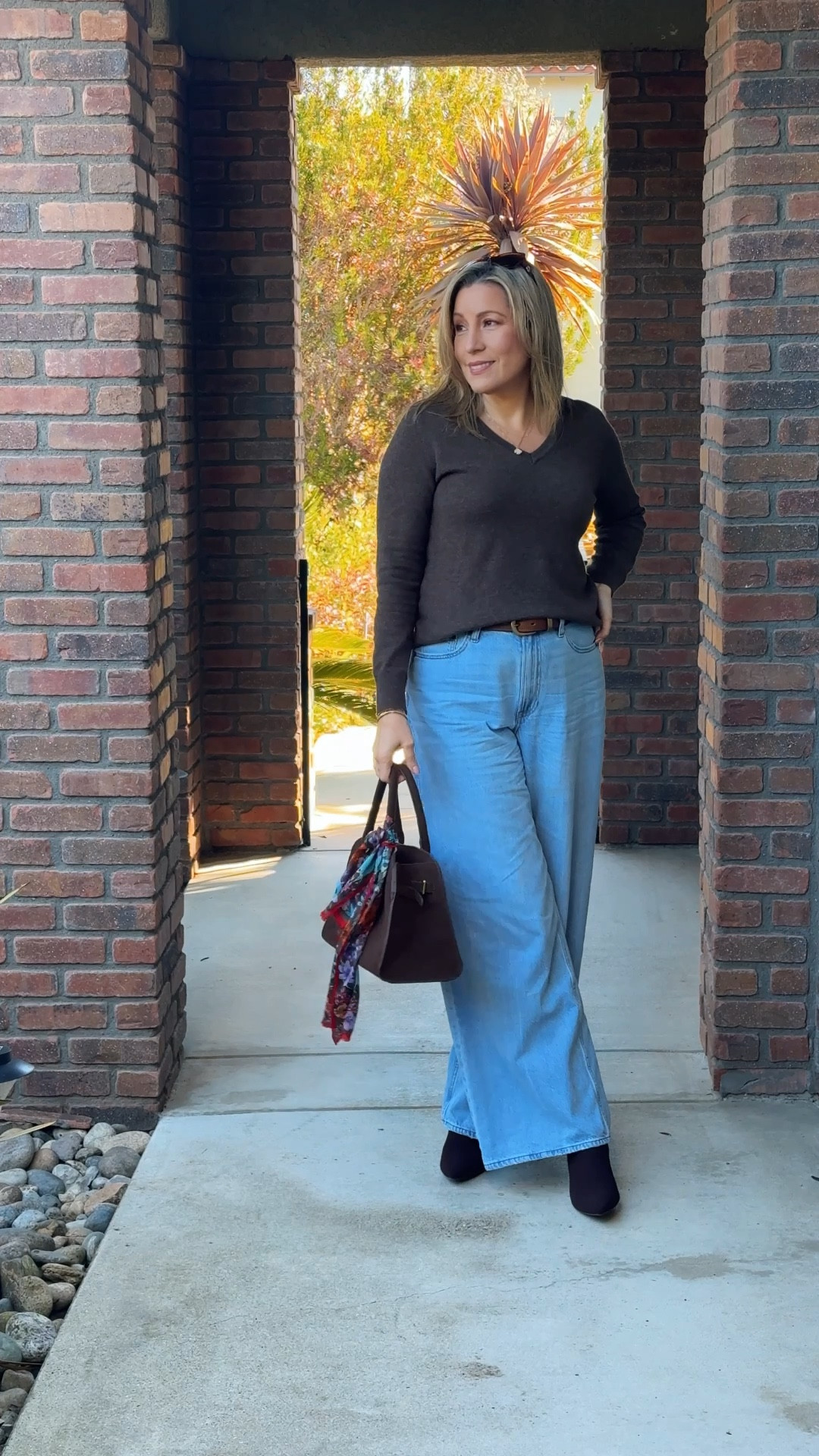 Subtle sophistication with warm brown accents 🤎 Featuring a cozy cashmere V-neck sweater paired with wide-leg light-wash jeans for a relaxed yet refined look. Accessorized with a rich brown handbag adorned with a red patterned scarf for a pop of color and sleek brown boots for a polished finish. Perfect for a crisp day ❄️🍂 #fallfashion #winterfashion #classicstyle #coolweather #effortlessoutfit #fashionover40 #stylishandgrateful

#LTKMidsize #LTKSeasonal #LTKOver40