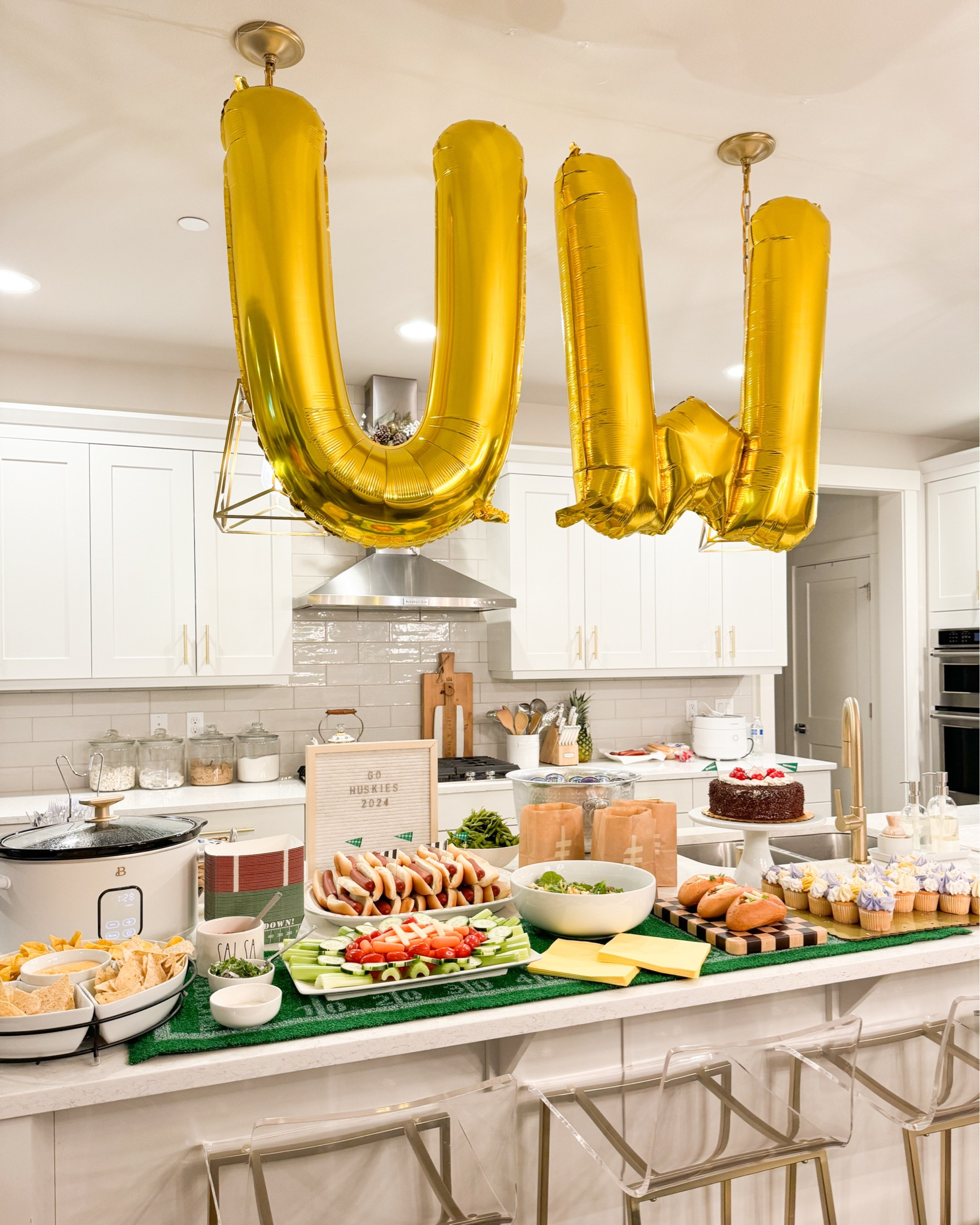Game day decor set up in kitchen. 

Super bowl Game Day Amazon Finds! Football turf table runner, slow cooker, bar stools, football party supplies, paper lunch bags, foldable charcuterie board, velveeta cheese


#LTKParties #LTKMostLoved #LTKHome