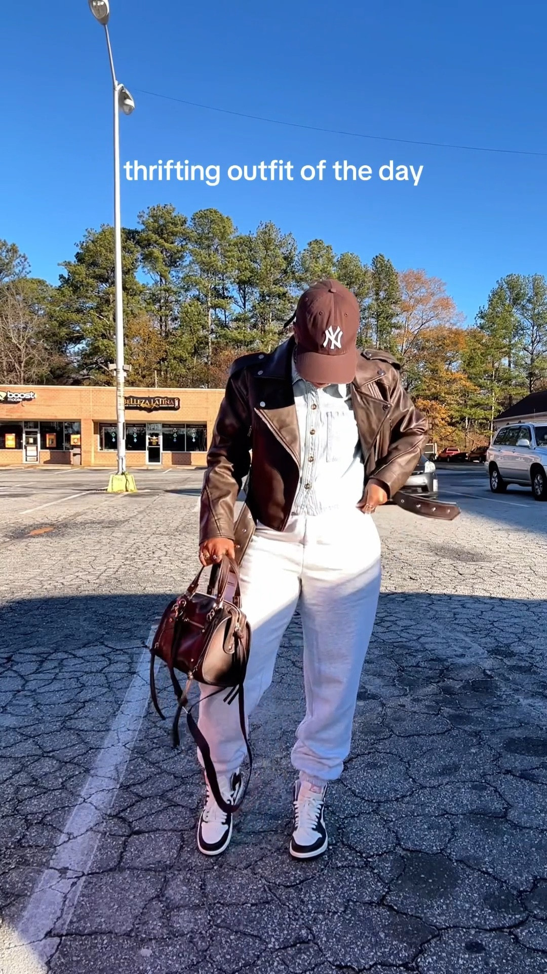 Thrifting outfit of the day. I’m wearing a brown faux leather jacket, brown ny hat, cropped denim button up shirt, grey jogger sweatpants, brown satchel bag, and brown and white Jordan 1 sneakers

#LTKPetite #LTKootd #LTKFindsUnder50