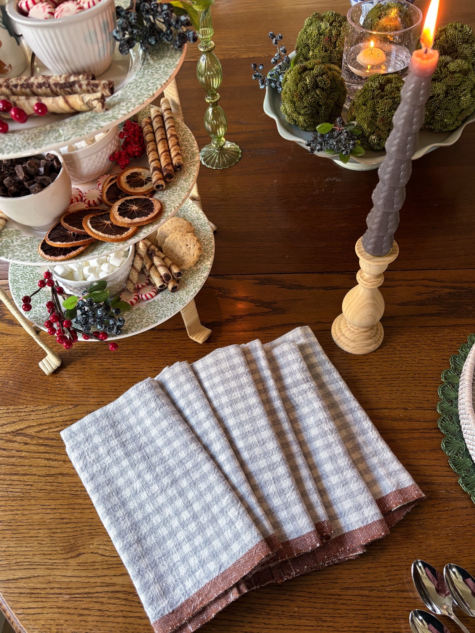 Gingham cloth napkins, rattan tiered serving stand with Spode dinner plates on it, wood taper candlestick, green glass candlestick, cake stand, moss balls 

#LTKHome #LTKHoliday #LTKSaleAlert