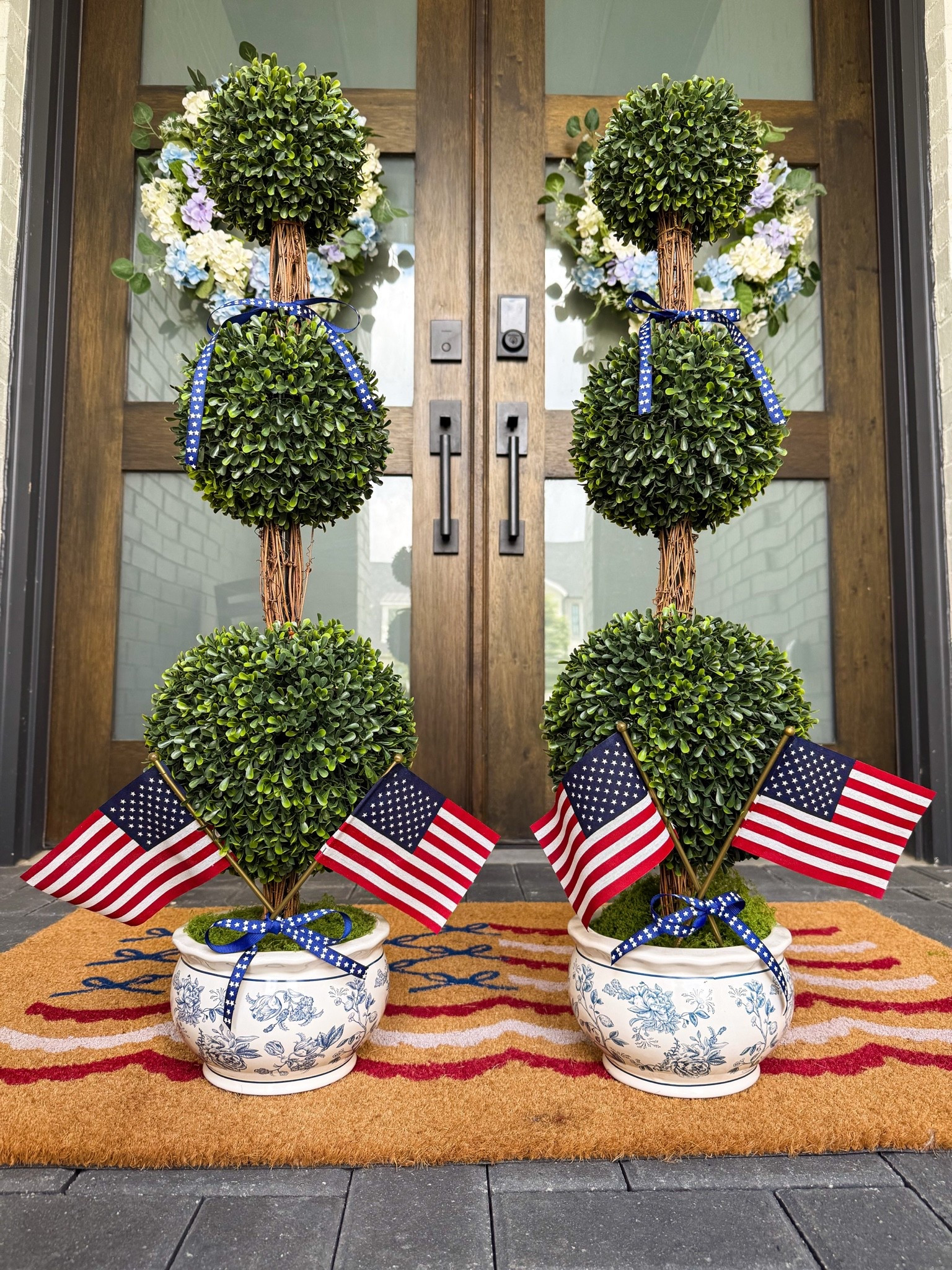 Patriotic front porch with topiary. Red, white, and blue decor with ribbon and flag.

#LTKHome #LTKSeasonal #LTKmomlife