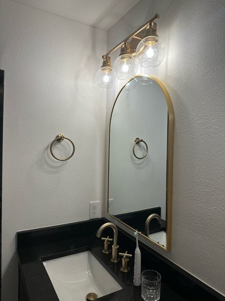 Gold bathroom accessories — arched mirror, hand towel holder, vanity light and widespread faucet — bathroom hardware 

#LTKhome