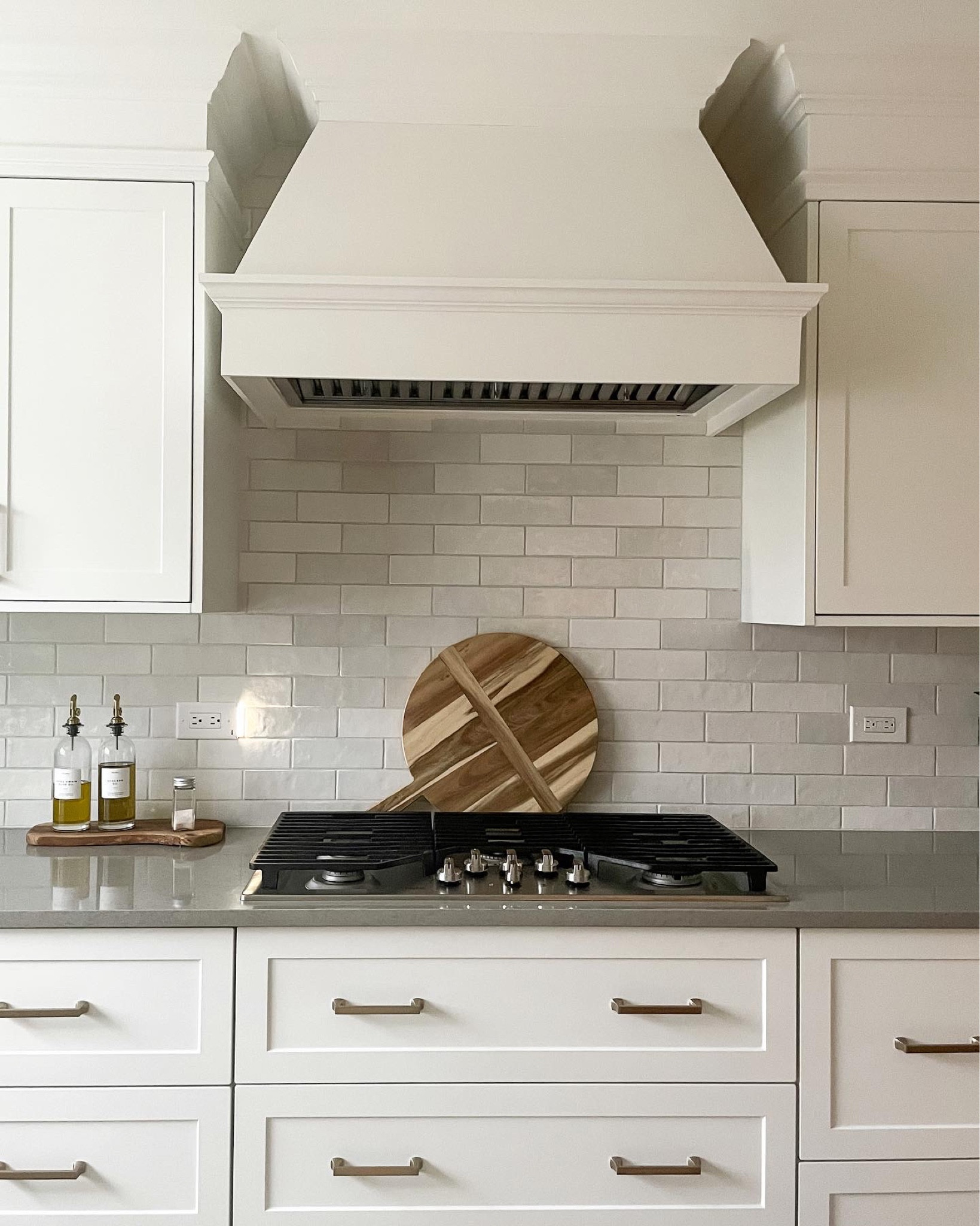 White kitchen design. Transitional style. Home decor. Olive oil bottle. Subway tile. Kitchen backsplash. Cooktop. Range hood insert. Charcuterie board. Cutting board. Wooden riser. Drawer pull. Hardware  

#LTKhome #LTKFind