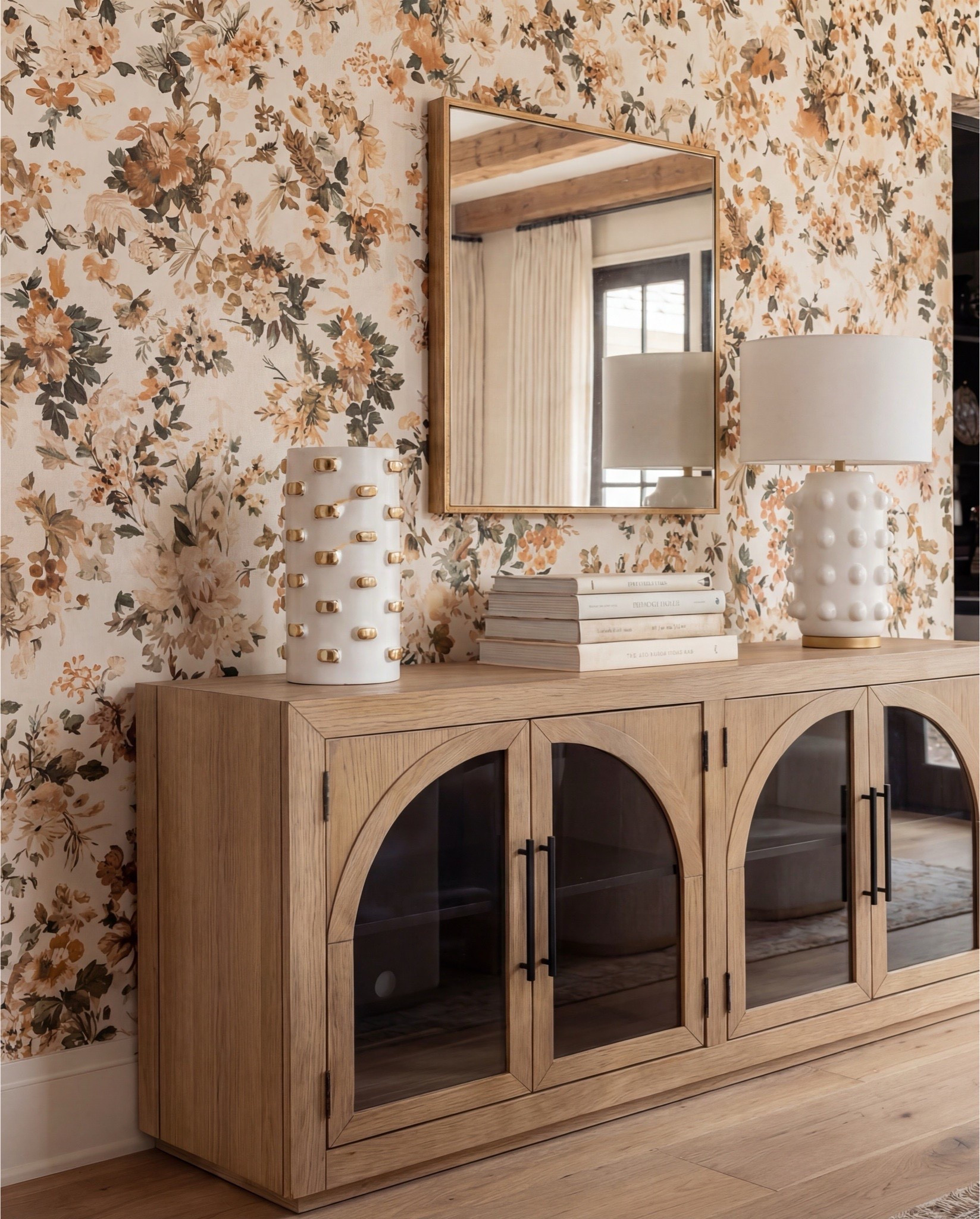 Shop the Look:
• Warm oak dining table
• Curved ivory dining chairs (brass base detail)
• Brass + globe statement chandelier
• Soft floral wallpaper (warm neutrals + terracotta)
• Oak sideboard with arched glass doors
• Textured ceramic table lamps + decor
• Neutral vintage-style area rug
• Gold trays + candle set
• White ceramic serving bowl


#LTKSaleAlert #LTKHome