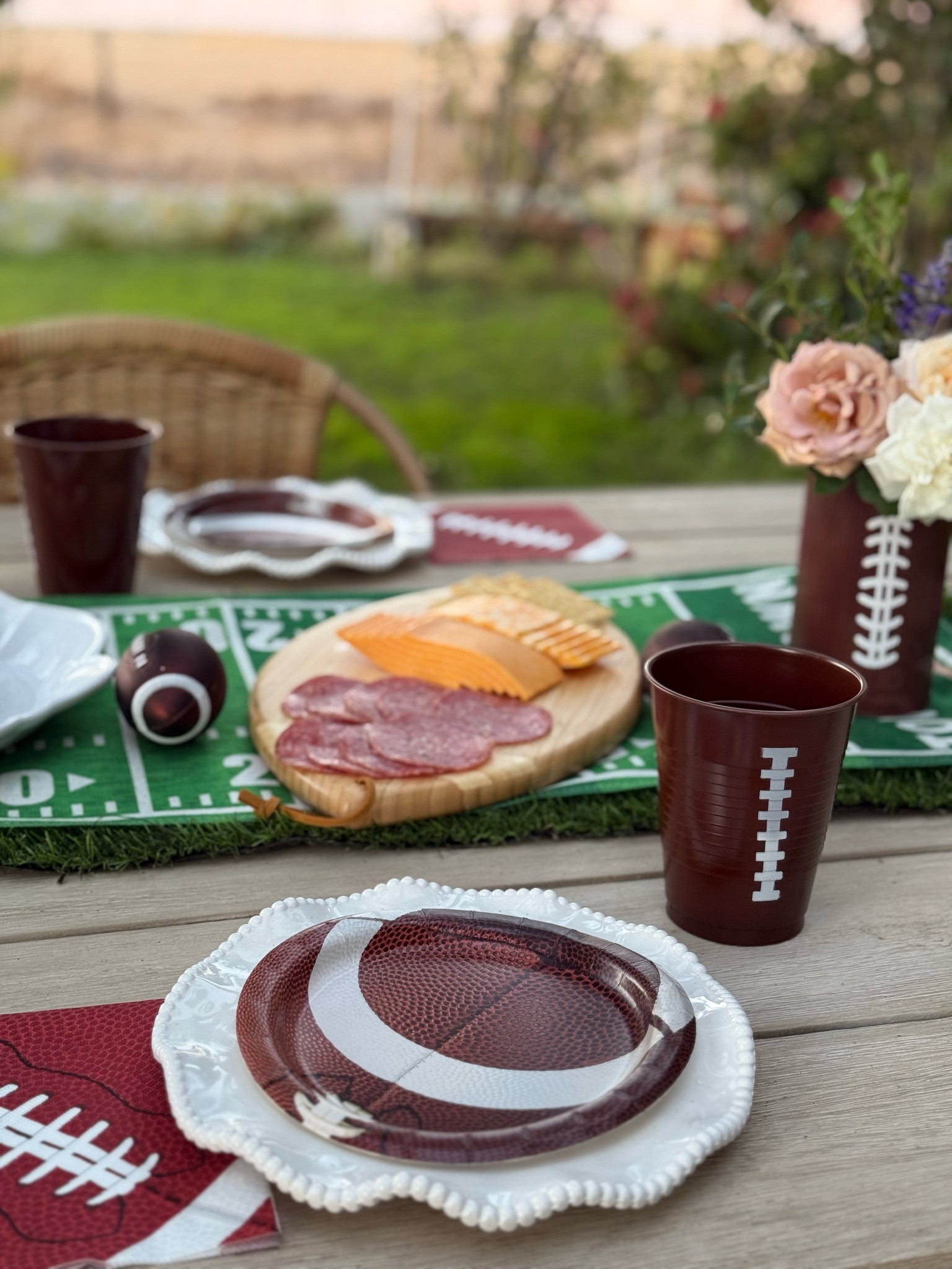 The best football tailgate tablescape! I love football paper plates, football plastic cups, football vases filled with fresh flowers, the touchdown table runner, faux grass runner adorning the table and football shaped charcuterie board! This is perfect for Friday night lights, College football Saturday, Sunday night football, Monday night Football, Thanksgiving, the NFL playoffs, the Super Bowl (big game) and more! 🏈❤️ 

#LTKParties #LTKHome #LTKSeasonal