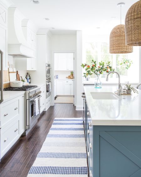 Love all the natural light in our previous coastal inspired kitchen! Items include a blue and white striped rug, oversized woven rattan pendants, a glass vase with faux orange branches, blue and white wicker barstools, a chrome faucet and chrome cabinet knobs and pulls. Other items include oversized wood charcuterie boards, a cookbook stand and a white Dutch oven. 

Coastal kitchen, bar stools, neutral decor, kitchen runner, kitchen island design, kitchen island lighting, kitchen knobs, kitchen hardware, kitchen light pendant, kitchen island pendents, kitchen chairs, kitchen bar stools, kitchen rugs, kitchen counters, amazon kitchen, kitchen accessories, cutting boards, serena and lily kitchen, kitchen counters, island bar stools, amazon finds, amazon home, pottery barn kitchen, Serenaandlily rugs, kitchen vases, williams sonoma, coastal decorating, coastal design, coastal inspiration    

#LTKSeasonal #LTKstyletip #LTKunder50 #LTKunder100 #LTKsalealert #LTKhome #LTKfamily #LTKFind #LTKhome #LTKSeasonal #LTKsalealert