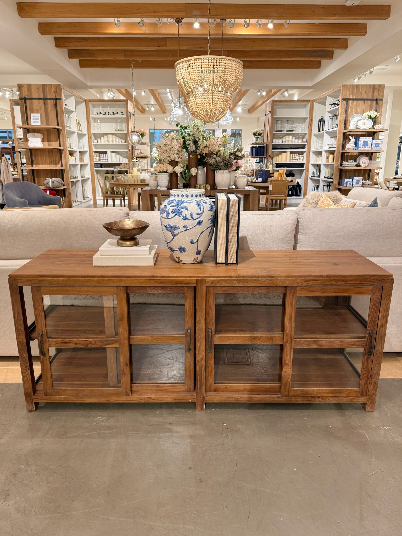 Such a beautiful way to style a space! 😍 The Menlo Reclaimed Teak Console Table brings warmth and character with its rich medium-brown wood and naturally aged details. 🤎 Styled here behind the couch with a blue-and-white floral vase, stacked books, and a brass pedestal bowl, it feels fresh, layered, and effortlessly inviting.✨ The sliding glass cabinet doors make it easy to mix decorative accents with hidden storage, while still keeping everything visually light and styled. ☺️ I’ve linked this console along with similar styles to recreate this cozy, collected look! 🫶🏻 #LivingRoomInspo #Credenza #PotteryBarn

#LTKHome #LTKSaleAlert