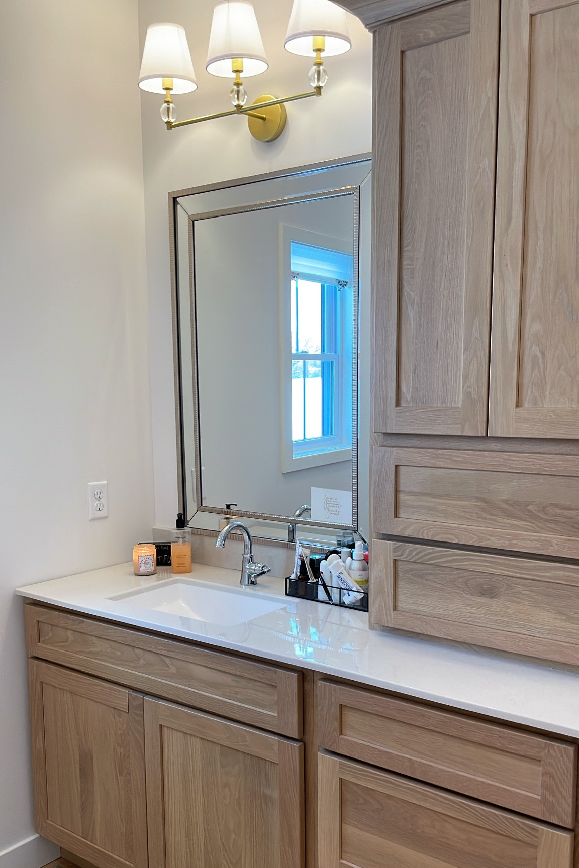 Master bathroom vanity. While oak cabinetry paired with Crome faucet, Crome mirror, gold vanity light with white shades. 

#LTKbeauty #LTKhome #LTKstyletip