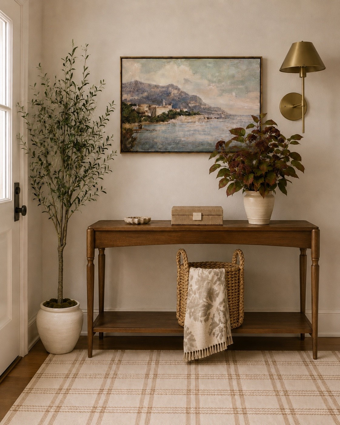 This entryway is giving warm, collected and suspiciously put together 🤎 The wood console table, landscape artwork, brass sconce, faux olive tree, woven basket, neutral rug and fall stems create such a cozy, elevated first impression. Basically proof that an entryway can be functional and pretty—because apparently we’re allowed to have both.

Entryway decor, entryway table, console table, wood console table, narrow console table, entryway styling, foyer decor, foyer table decor, hallway decor, neutral home decor, warm neutral decor, traditional home decor, transitional home decor, organic modern decor, cozy home decor, elevated home decor, classic home decor, entryway wall art, landscape wall art, framed landscape art, coastal landscape art, vintage inspired wall art, brass wall sconce, gold wall sconce, entryway lighting, faux olive tree, artificial olive tree, indoor faux tree, decorative planter, ceramic planter, fall floral arrangement, faux fall stems, neutral vase, ceramic vase, woven basket, storage basket, blanket basket, decorative throw blanket, neutral throw blanket, plaid area rug, neutral area rug, entryway rug, decorative box, lidded storage box, console table decor, small decorative bowl, Amazon home decor, home decor finds, small entryway ideas, entryway inspiration

#LTKSeasonal #LTKHome