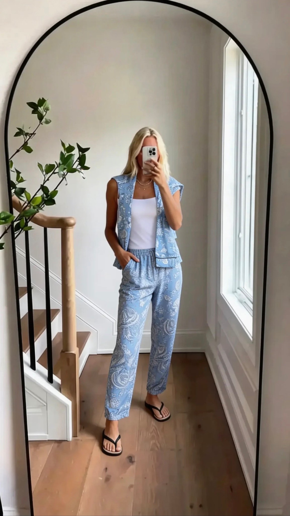 Minimalist mirror selfie of a blonde woman wearing a light blue paisley matching set with a sleeveless vest and relaxed pants, styled with a white tank and black flip flops, soft natural lighting, neutral modern home interior, wood floors, clean aesthetic, effortless summer style, coastal chic vibe, casual luxury, Pinterest-worthy composition, full-body framing, lifestyle fashion content

Hashtags:
#summerstyle #coastalchic #effortlessstyle #ootd #resortwear #matchingset #neutralaesthetic #pintereststyle #traveloutfit #casualluxury #minimalstyle #everydaychic #vacationvibes #styleinspo #lookbook

Words (with /):
coastal / breezy / effortless / relaxed / polished / minimal / chic / soft / airy / neutral / elevated / casual / modern / clean / feminine / travel-ready / resort / light / fresh / timeless / simple / laid-back / stylish / everyday / summer

#LTKFestival #LTKgrwm #LTKdayinmylife