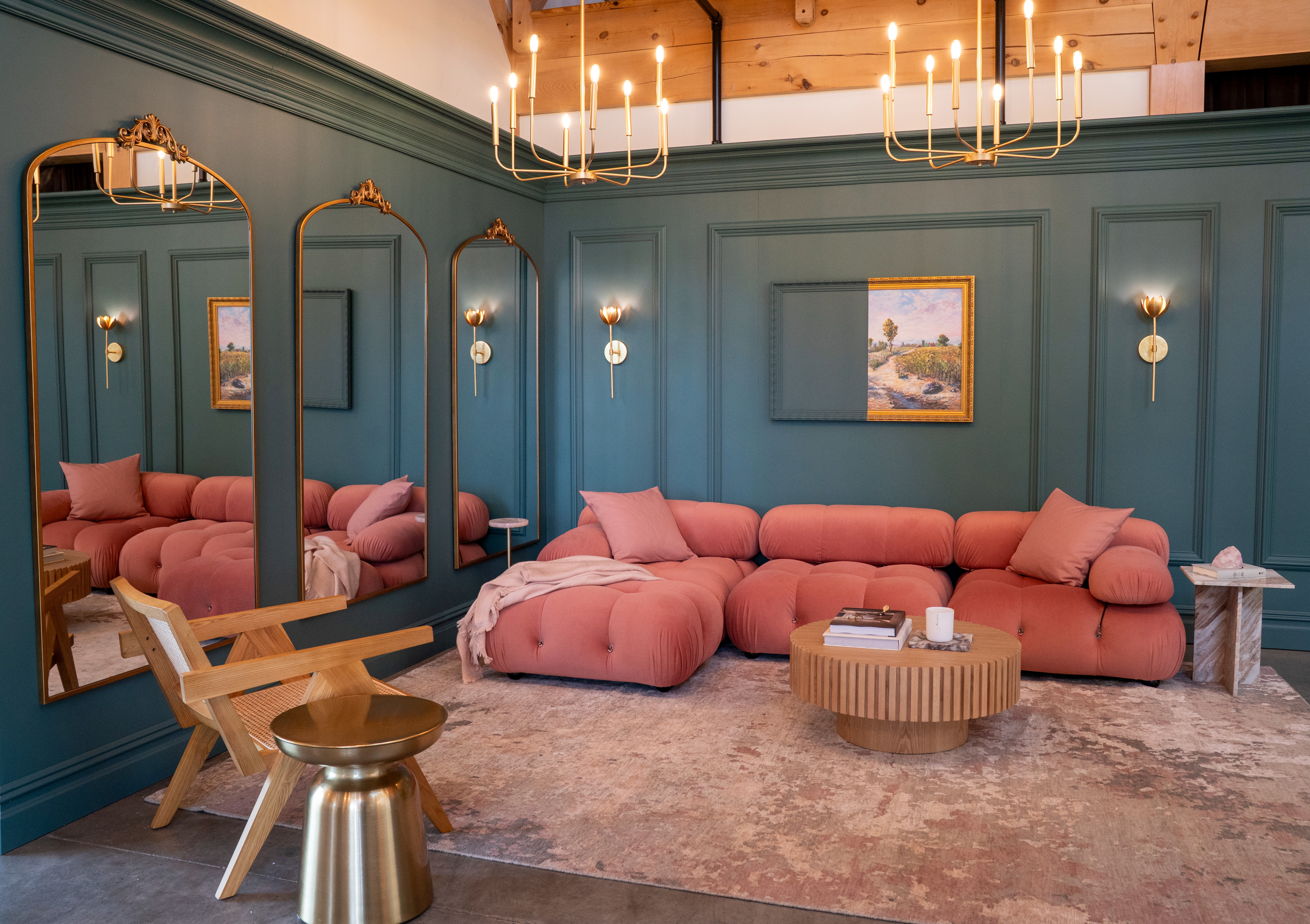 A Parisian-inspired living room with walls painted in Behr Hidden Gem, featuring traditional mouldings, crown detailing and three full-length mirrors. A pink Mario Bellini–inspired sofa, a Pierre Jeanneret–inspired cane chair, modern tables and two wall sconces framing artwork create a chic blend of classic and contemporary design. 

 #LTKCyberWeek #LTKGiftGuide #LTKHome