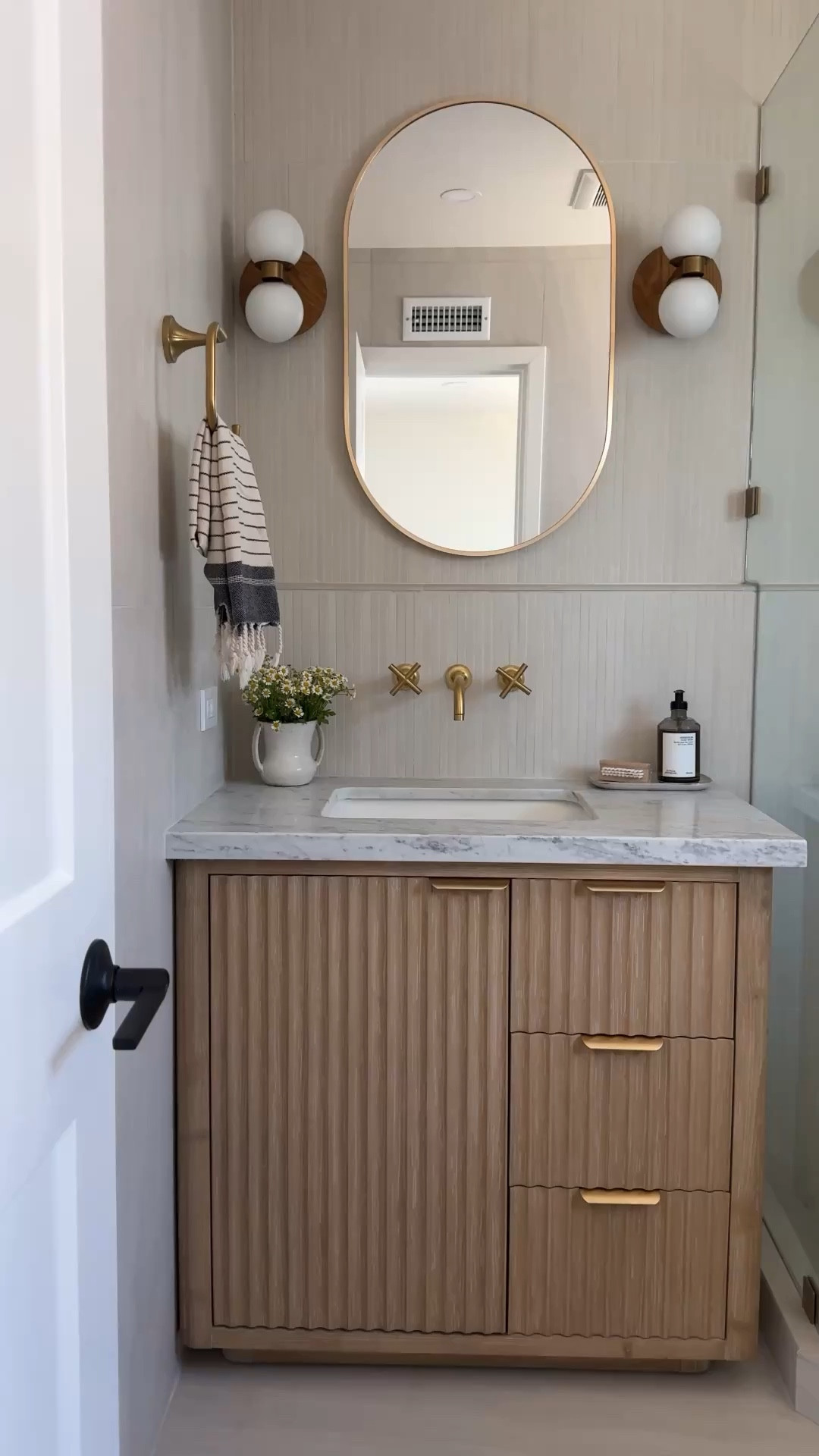 Can you believe this vanity isn't custom? It has
organized compartments in the drawer, soft close, and the prettiest wood fluted detail. Comes with a countertop and without. This entire bathroom is from Wayfair.

Brass hardware wood vanity white tile grey tile brass shower system bathroom accessories medicine cabinet black rectangle mirror oval capsule sconces lights

#LTKHome #LTKSaleAlert