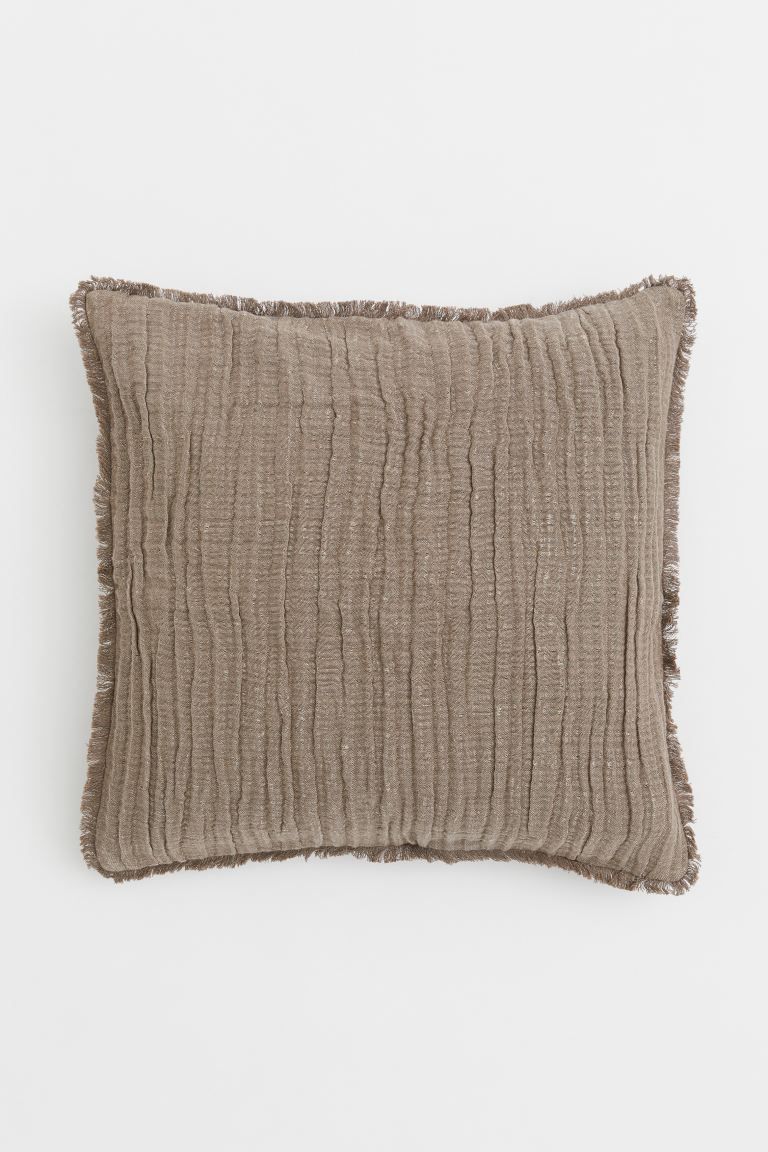 Conscious choice  Crinkled cushion cover in a soft, woven linen and cotton blend with raw-edge fr... | H&M (US + CA)