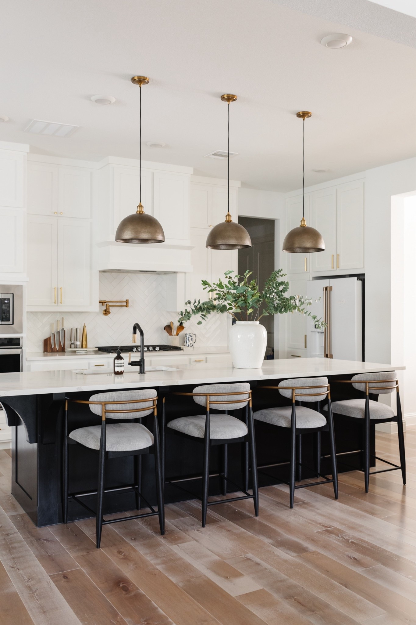 Transitional kitchen at my parents’ home with brass dome pendant lights above the kitchen island and upholstered counter stools with arms to make it easier for them to get in and out of. Love the black and brass kitchen faucet and pot filler. 

#LTKHome