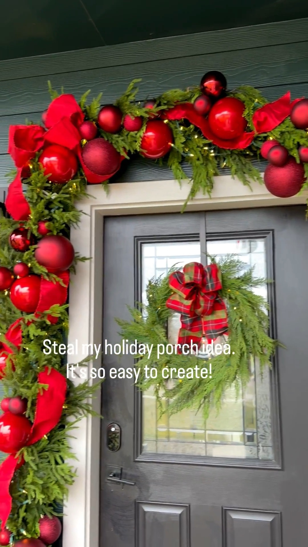 Create a show-stopping front porch this year.  It only took me about an hour to assemble it.
I started with a natural greenery garland then layered in two Norfolk pine artificial garland. I added in a variety of red ornaments in clusters of 3, then topped it off with a long tail bow (4" ribbon).   