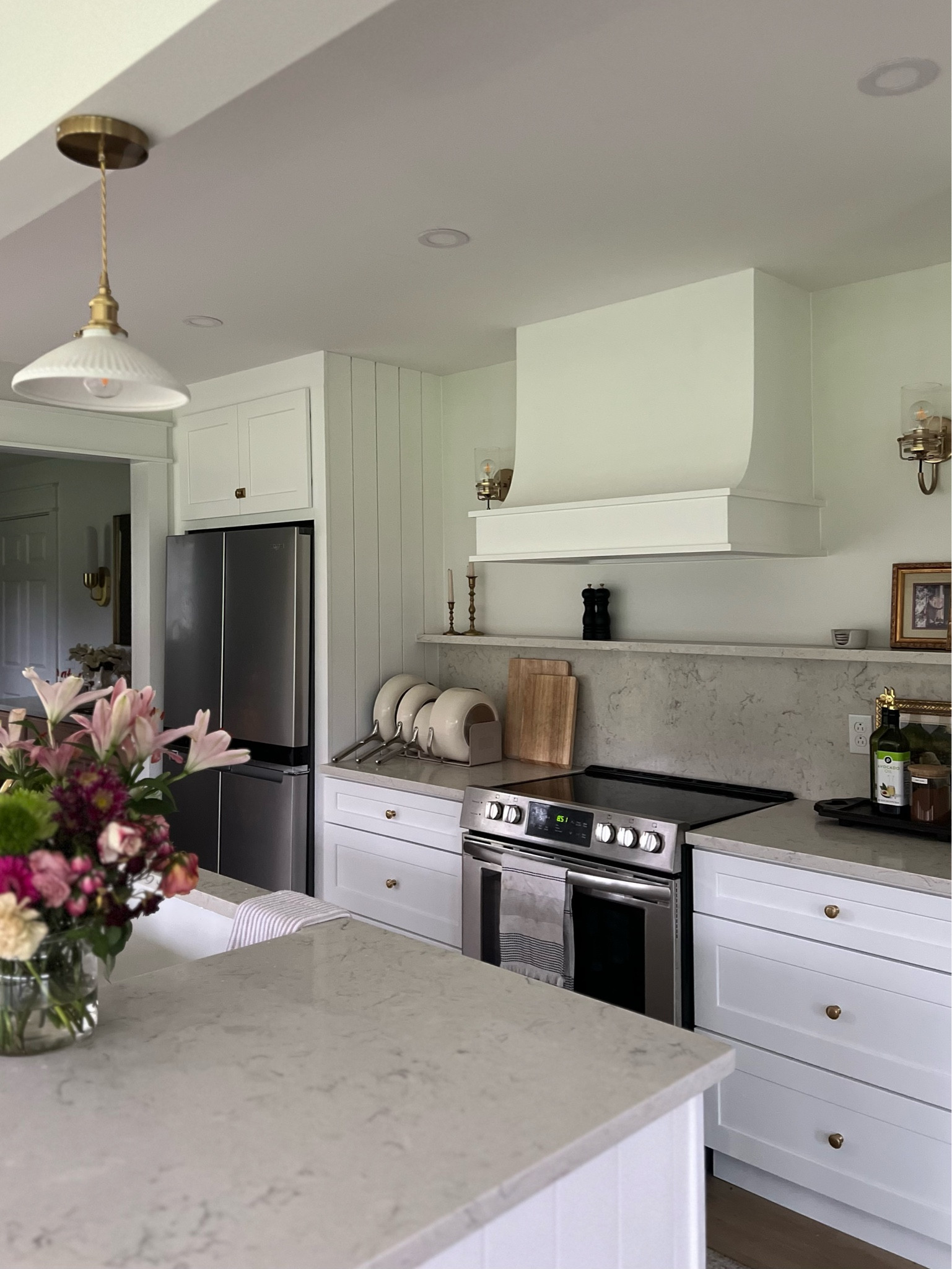 Embracing timeless elegance in our country home with a pristine white kitchen that exudes charm and sophistication. Our custom hood takes center stage, adding a touch of bespoke luxury, while the vertical paneling infuses rustic warmth into the space. The marble-like quartz backsplash lends a hint of opulence, perfectly complementing the crisp white cabinets. And let's not forget the sleek floating shelf, a minimalist's dream come true, effortlessly combining style and functionality. Step into our sanctuary of culinary inspiration, where classic design meets contemporary flair, and every detail tells a story of effortless grace and enduring beauty. 

#LTKhome #LTKsalealert #LTKstyletip