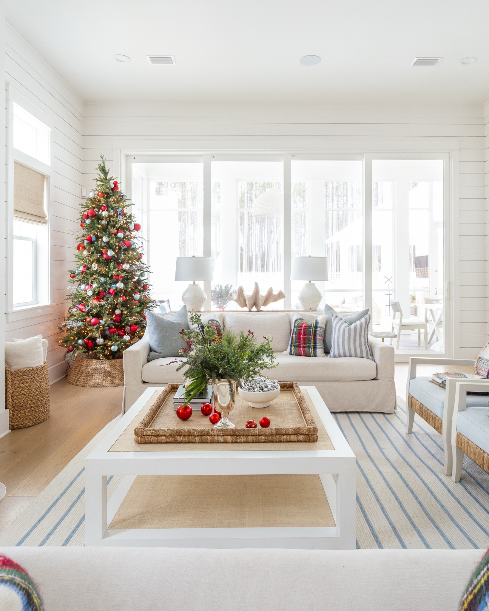 Our cozy coastal Christmas living room with linen sofas, blue and white striped rug, red Stewart plaid throw pillows, a 9' Christmas tree with red and silver ornaments, evergreen stems in a silver trophy vase, a raffia coffee table and cozy throw blankets. #ltkholiday #ltkhome #ltksalealert #ltkfindsunder50 #ltkfindsunder100 #ltkstyletip #ltkseasonal 

#LTKSaleAlert #LTKHome #LTKHoliday