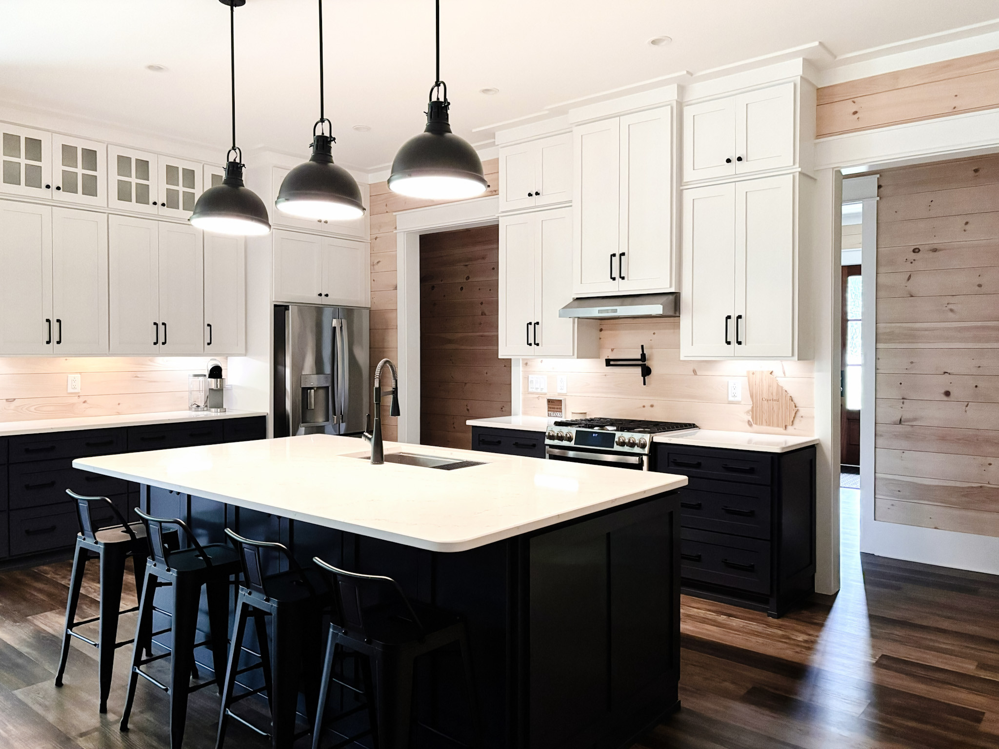 ✨ A kitchen made for feeding a crowd and gathering after a long day outdoors. This hunting lodge kitchen blends classic black-and-white cabinetry with warm wood shiplap, industrial pendants, and a generous island that invites everyone to pull up a stool. Timeless finishes meet rugged charm, creating a space that feels both elevated and hardworking—perfect for family meals, card games, and late-night stories.

Shop a similar look to bring this cozy lodge-inspired style home.
 #HuntingLodgeStyle #KitchenInspo #CabinKitchen #ShopTheLook 

 #LTKHome