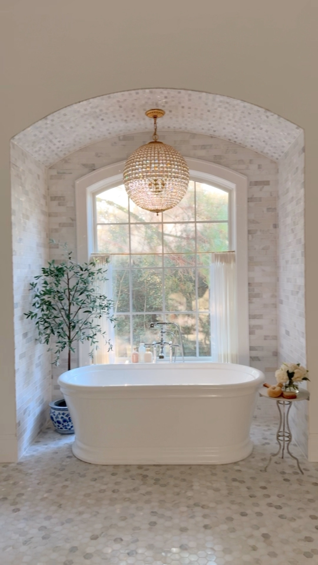 Primary bathroom 
Chandelier, tub faucet, olive tree, vase, planter