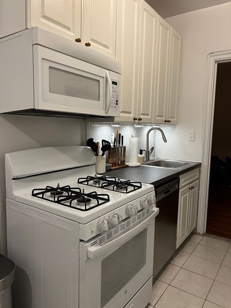 4 RENTER & BUDGET friendly kitchen updates we’ve made so far…

✨New kitchen knobs: I couldn’t believe how big of a difference these made to the cabinets. And after giving the doors a decent wipe down, I love the way now look. I opted for an antique looking one because we’re going towards a classic theme for the overall kitchen aesthetic. 
✨Faux soapstone contact paper: this was more of a challenging and time consuming project but with some patience, it was well worth it. The old countertops were old and just blah looking (and no matter how much I cleaned they still looked dirty 🫠). Pro tip: spray the sticky side with all purpose cleaner so it can be easily moved while installing. 
✨Peel & stick tile backsplash: I made a Reel about this already and still loving these @smarttiles.official. 
✨Magnetic motion sensory lights: this changes the entire mood of the kitchen and they’re rechargeable! 