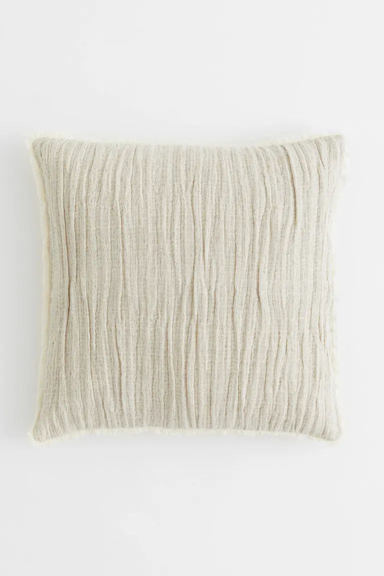 Conscious choice  Crinkled cushion cover in a soft, woven linen and cotton blend with raw-edge fr... | H&M (US + CA)