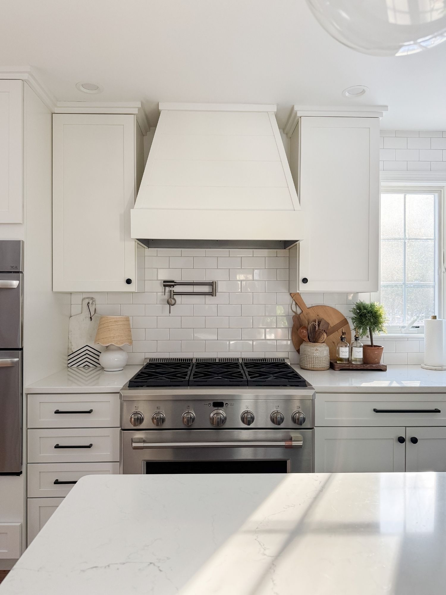 A timeless cape cod coastal kitchen moment with a custom hood, classic subway tile, and warm layered accessories that keep the space feeling both functional and styled. Neutral tones and natural textures create a calm everyday kitchen. Cape cod kitchen design, coastal kitchen range styling, white subway tile kitchen, neutral kitchen decor, amazon finds kitchen accessories, coastal neutral home, sherri calnan home

#LTKHome
