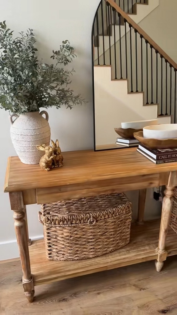 My entryway is one of my favorite little moments in our home 🤍 I wanted it to feel warm, welcoming, and styled without feeling cluttered.

This wood console table is the perfect anchor piece and adds so much warmth with the natural tones. I layered a tall arched mirror behind it to reflect light and make the space feel bigger, especially with the natural light coming through our front door.

For styling, I always like to mix height, texture, and a few cozy details. On one side I stacked a couple coffee table books and topped them with a small wood bowl and marble dish for an easy layered look. On the other side, I kept things simple with a neutral wood vase and a few faux stems for some greenery.

The glass lamp with the wood bead tassel brings in soft lighting and another natural texture that ties everything together. I finished the look with woven baskets underneath the console for extra storage (and they add the prettiest texture).

It’s a simple, neutral entryway that feels calm, cozy, and welcoming the moment you walk in 🤍

Everything is linked here if you want to recreate the look!
#entrywaydecor #neutralhome #ltkhome #modernfarmhousestyle #entrywayinspo #homedecorideas

#LTKHome #LTKSaleAlert #LTKSeasonal