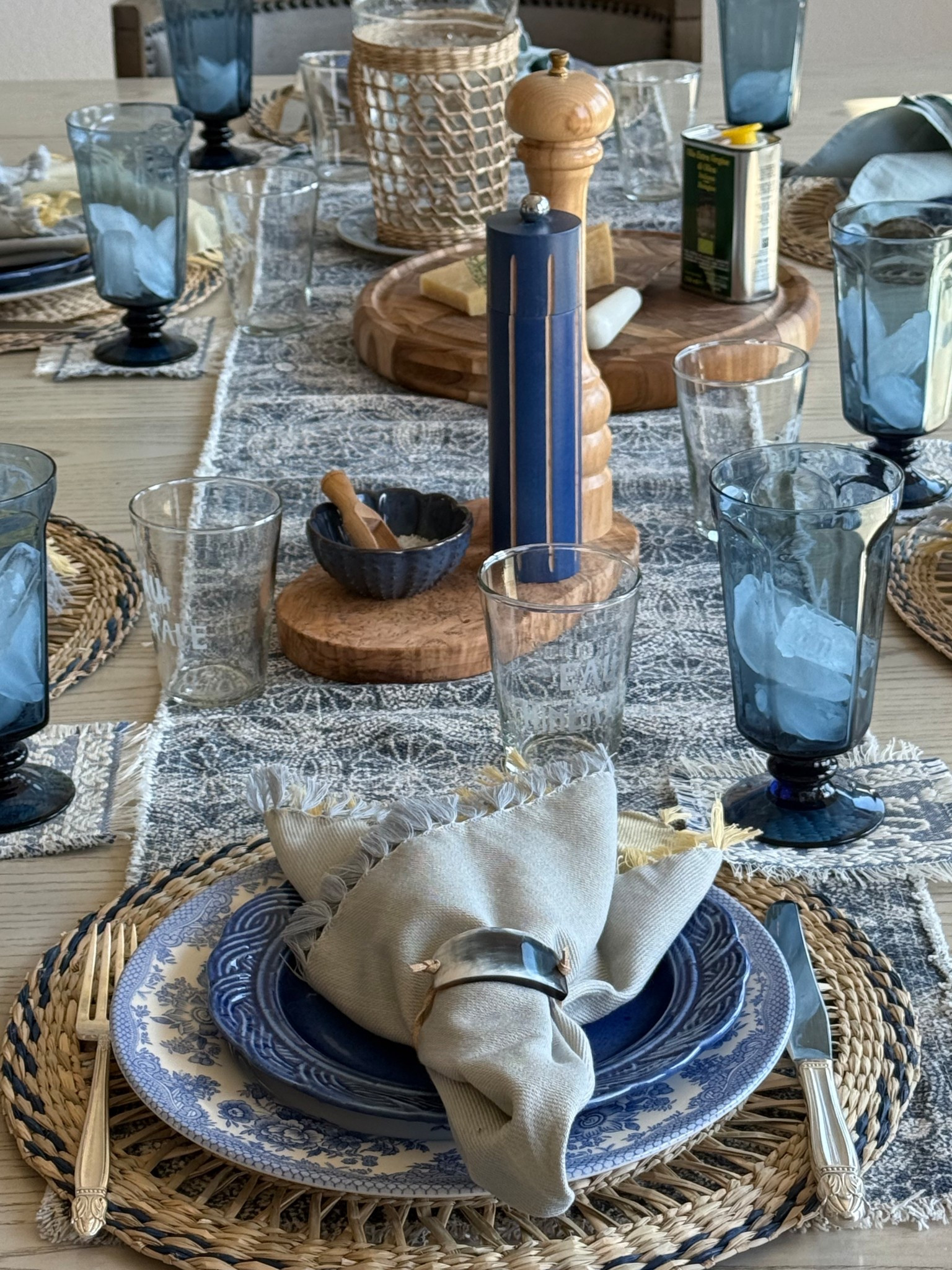 A Provençal evening at the table — woven chargers layered with blue-and-white china, napkins in sun-washed yellow and sky-tinted blue, rustic horn rings, and bistro-style Eau Minérale glasses.

#LTKFindsUnder100 #LTKStyleTip #LTKHome