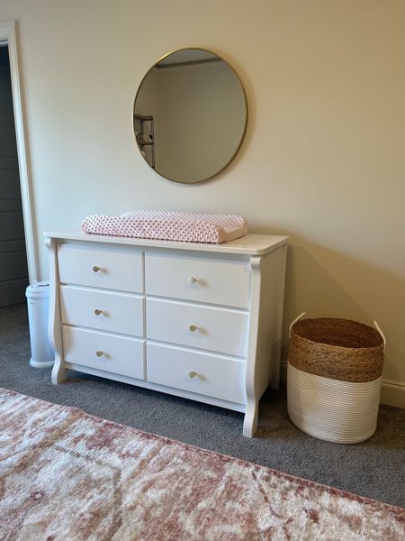 Baby girl’s nursery is coming along 🩷 Updated the dresser with gold knobs, switched out the mirror for a gold round mirror, added in a new rug and got new changing pad covers + laundry basket - gold round mirror is from Lowe’s and laundry basket is from home goods but linked similar items  

#LTKbaby #LTKhome #LTKfamily