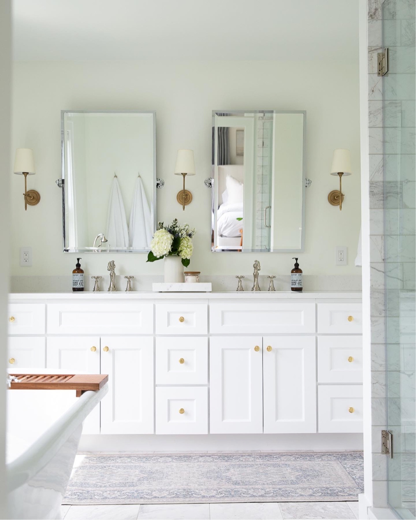 Master bathroom, primary bathroom, marble and white bathroom design, chrome pivot mirror, brass sconces, teak bathtub tray, washable bathroom runner, Ruggable, brass cabinet knob, neutral bathroom design, bathroom lighting, design ideas

#LTKstyletip #LTKhome #LTKsalealert