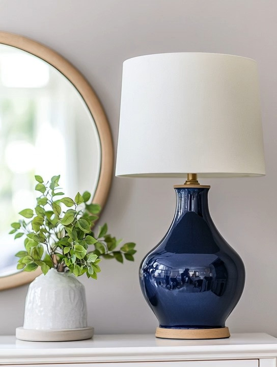 This navy table lamp brings a relaxed yet polished California coastal and nautical-inspired vibe into any space. The deep navy ceramic base adds richness and contrast, while the soft ivory lampshade keeps the look light, fresh, and timeless. It’s the perfect balance of classic and modern, making this lamp an easy styling piece for a living room, bedroom, entryway console, or home office.

A navy blue table lamp works beautifully with neutral palettes, light woods, whites, and soft grays, instantly adding depth without overwhelming the room. Whether styled on a console table with a mirror, on a nightstand, or on a side table next to a sofa, this modern navy table lamp adds warmth, character, and subtle coastal elegance—even when it’s turned off.

Simple, versatile, and effortlessly stylish, this navy base lamp is an easy way to elevate everyday home decor while keeping the space calm, curated, and inviting.

#navytablelamp
#coastalhomedecor
#moderndecor 

 #LTKHome