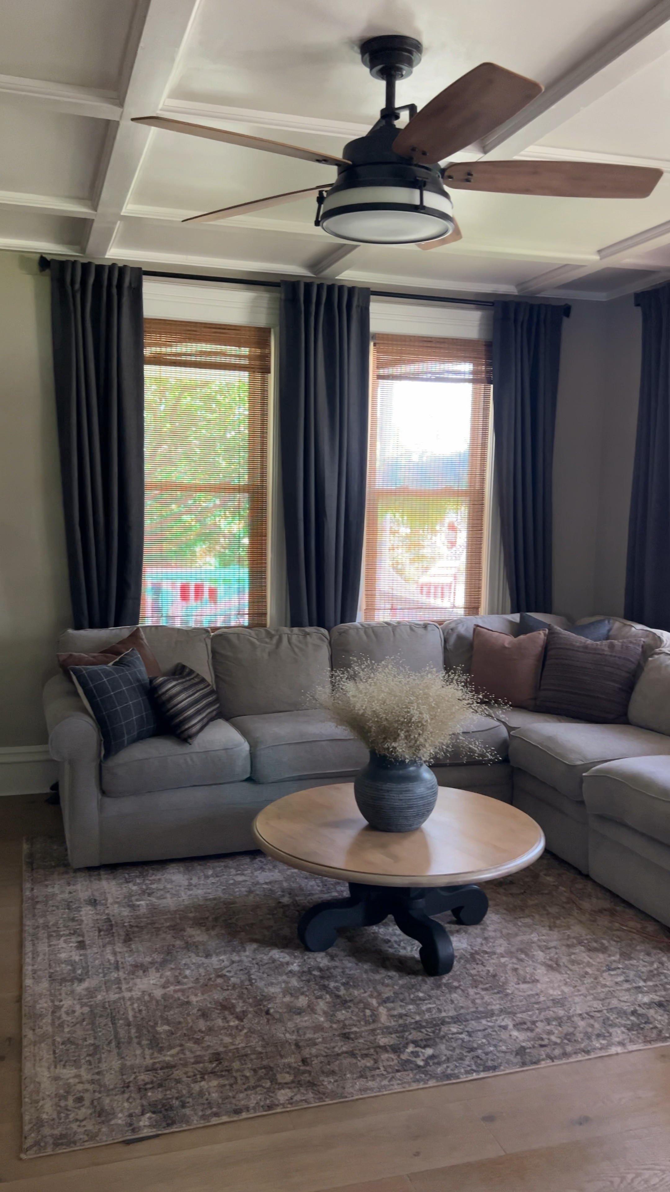 Woukd you believe me if I told you our front door used to be where the first window is?
It’s true, our living room transformation is pretty incredible. 
Adding these dark gray curtains and wooden woven blinds helped accentuate the tall ceilings. Paired with our moody throw pillows & vintage oriental rug it all pulls together nicely.
Follow @elevatedneutrals on IG, FB & Pinterest for our home inspiration.

Sherwin Williams Perfect Greige | Sherwin Williams Peppercorn | Coffered Ceiling | Moody Living Room | Neutral Living Room | Rustic Family Room | Traditional Home | Transitional Design | Modern Fan | Modern Lighting | Sectional Sofa | Simple Coffee Table Decor | Coffee Table Styling | Vintage Rug | Dark Gray Curtains | Wooden Blinds | Woven Wooden Shades | Hanging Vase | Pottery Barn | McGee & Co | Joss & Main | Collection Prints | Wayfair | All Modern | Afloral | Loloi Billie Oriental Rug | Brown | Gray | Color Scheme |


#LTKHome #LTKVideo