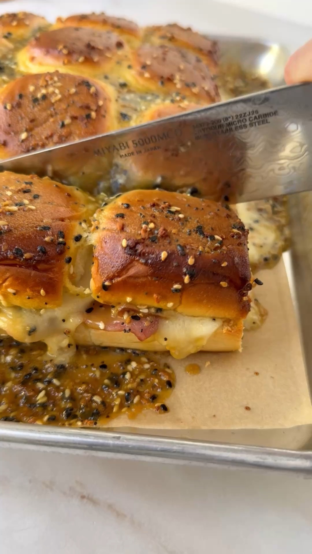 Ingredients
* 1 (12-roll) package King's Hawaiian Original Hawaiian Sweet Rolls
* 6 slices ham halved
* 6 slices Swiss cheese halved
* 6 slices turkey halved
* 6 slices provolone cheese halved
* 4 tbsp unsalted butter
* 2 tbsp honey
* 2 tbsp everything bagel seasoning
* 1 1/2 tbsp Dijon mustard
* 1 tsp flaky salt (I like Maldon)
Instructions 
* Preheat the oven to 350 degrees. 
* Remove rolls from package without breaking them apart into individual rolls. Slice crosswise to create a top and bottom layer. Arrange the bottom layer on a rimmed baking sheet. Top with ham in an even layer, then add even layers of Swiss, turkey, and provolone. Place the top layer of rolls over the ham and swiss. 
* Microwave the butter in a small microwave-safe bowl until melted. Once butter has melted, stir in honey, seasoning, and mustard. Drizzle or brush over tops of rolls. 
* Bake sandwiches until tops are golden brown and cheese is melty, about 15 minutes. 

#LTKfoodie #LTKSeasonal #LTKHome