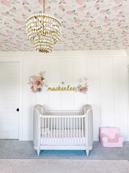 Feminine pink and white floral baby nursery with gold details. Magnolia home floral wallpaper on ceiling and white wainscoting on walls. Soft a pink vintage style area rug from Amazon. Perfect space for little girls  

#LTKhome #LTKfamily #LTKbaby
