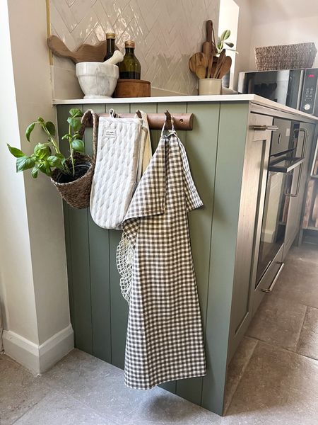 Kitchen storage for kitchen utensils and tea towels on a peg rail for hanging baskets and oven gloves. Wooden chopping boards, salt and pepper pot and pestle and mortar. Wooden spoons in a utensils pot 

#LTKeurope #LTKhome #LTKFind