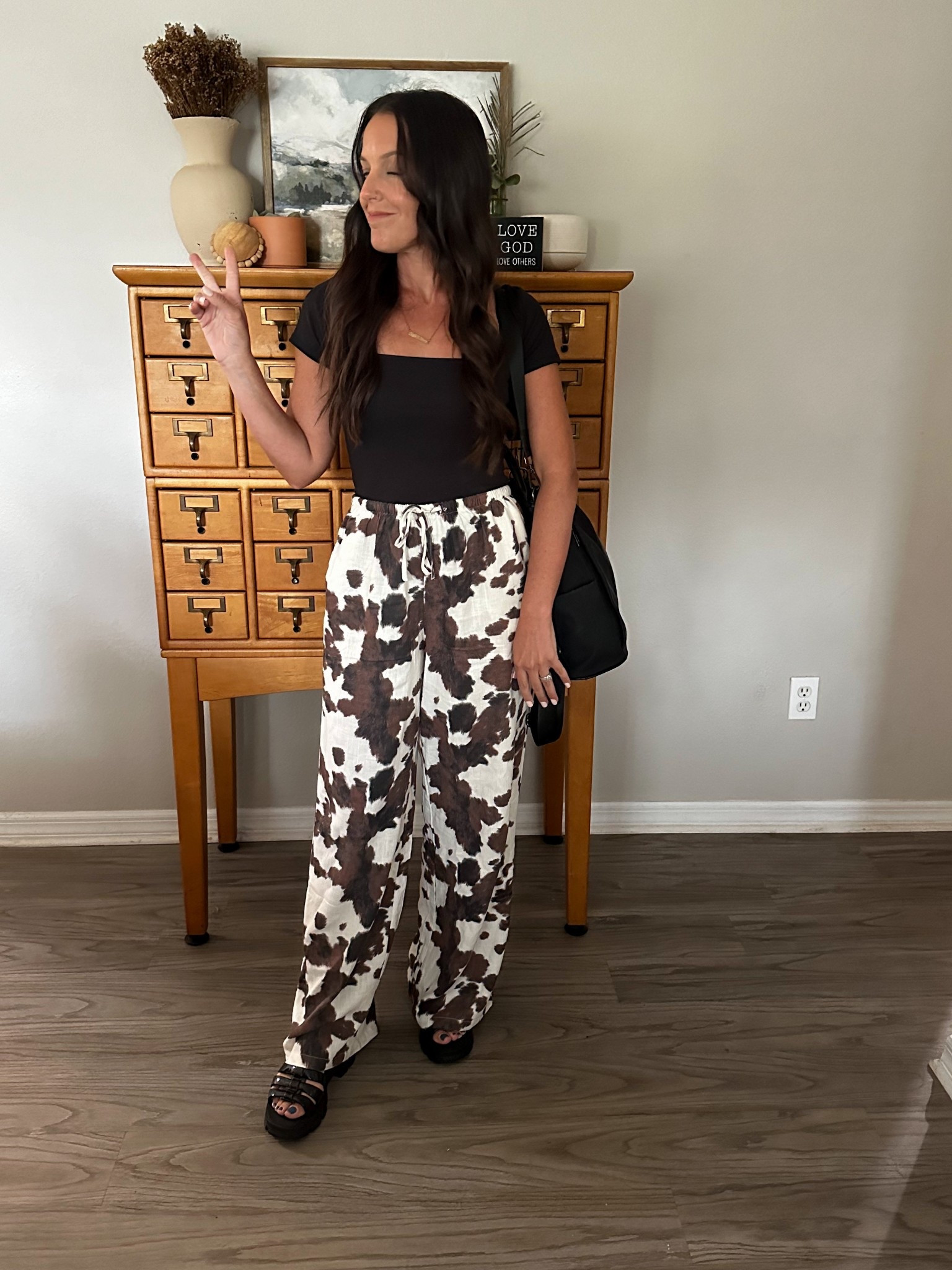 Cow print pants 
Black glossy chunky high sandals
Black form fitted top
Black purse & backpack in-one

#LTKStyleTip #LTKItBag #LTKShoeCrush